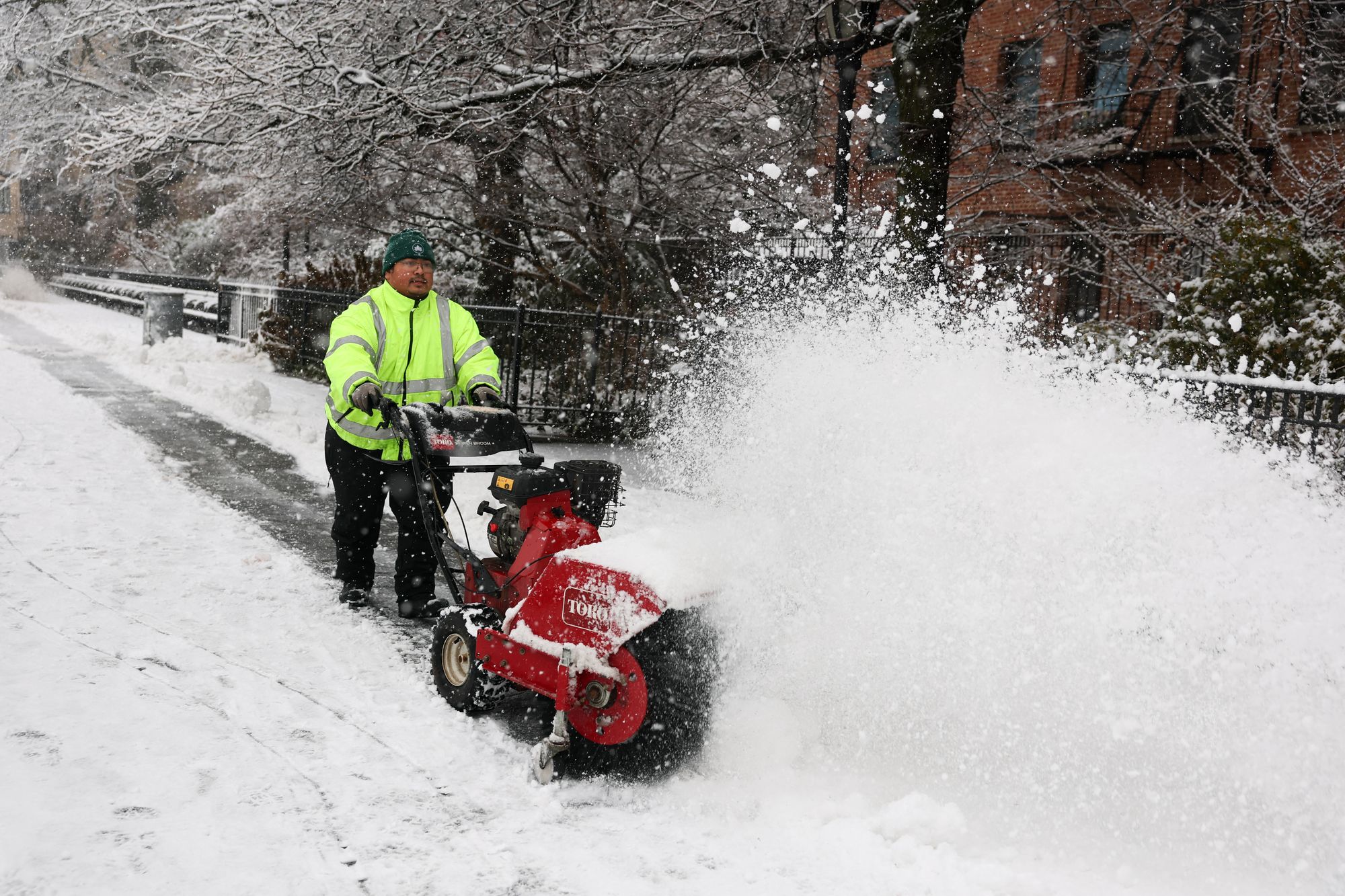 A municipal employee removes snow in a street as the snow falls in the Brooklyn borough of New York City