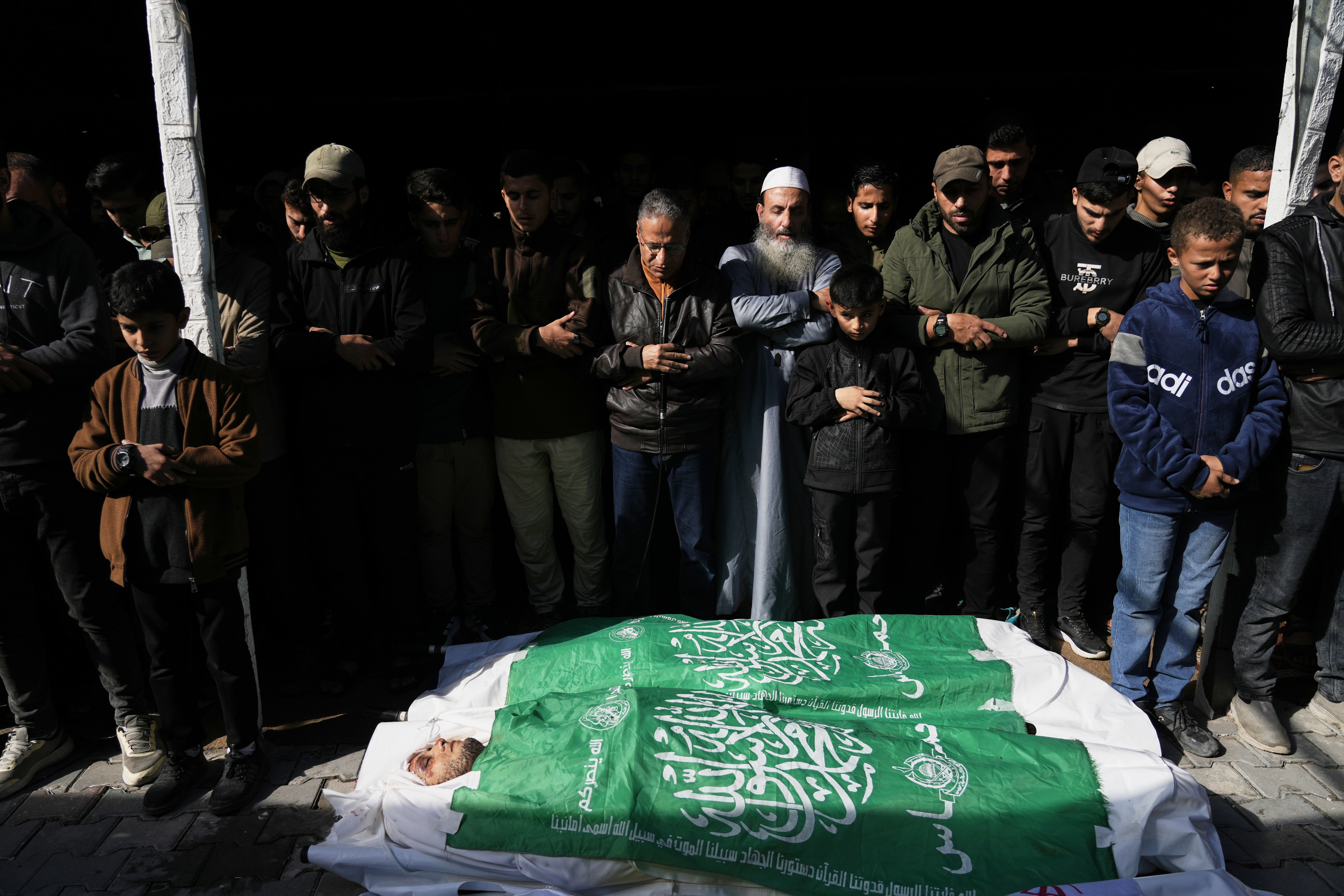 Palestinians pray during the funeral of Hamas' Al-Qassam Brigades operatives, whose bodies are draped in the group's flag, killed in an Israeli strike Saturday, in Gaza City on Saturday 14 December