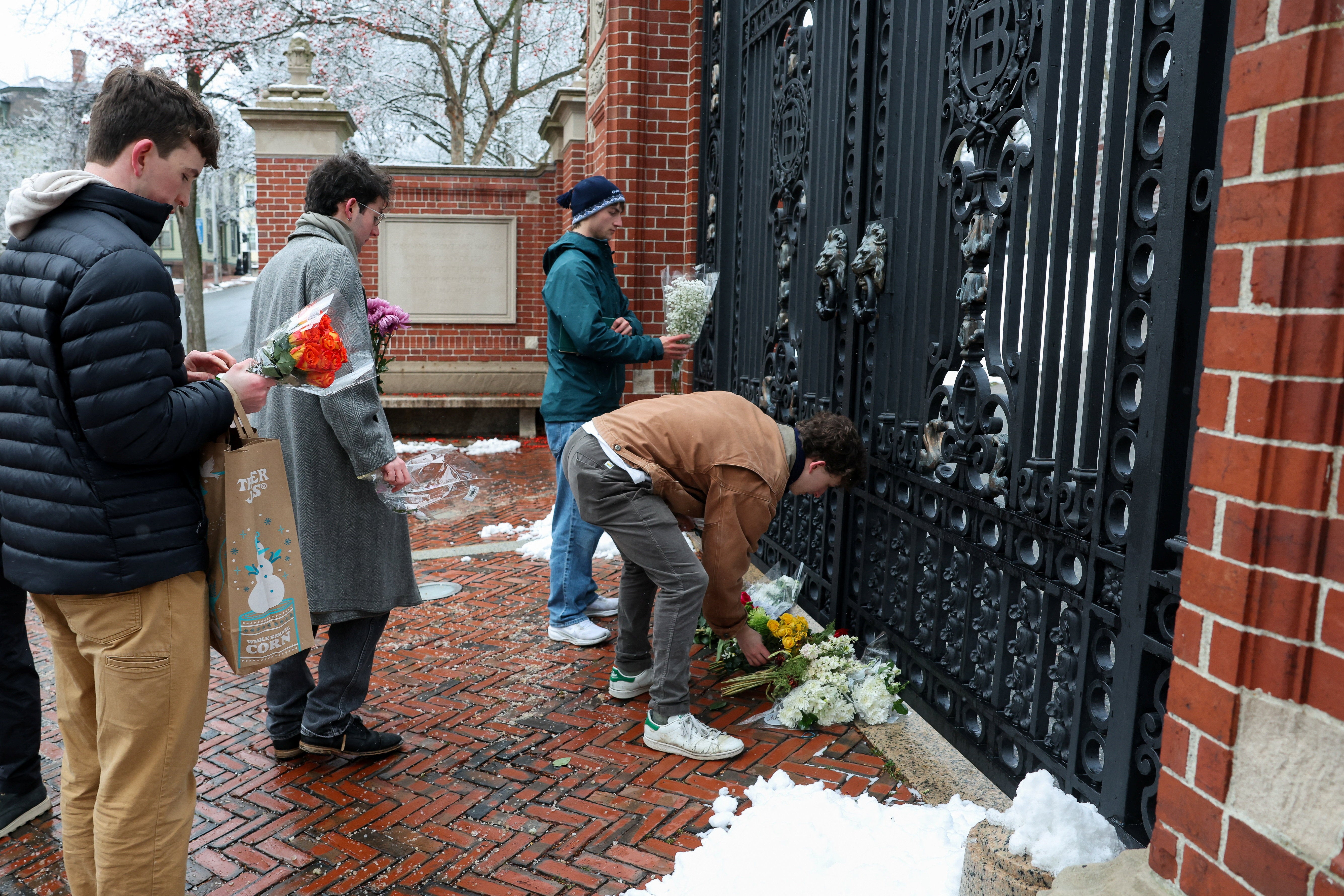 People placed flowers at the gates of Brown University December 14 as officials announce a interest is in custody following a mass shooting on campus that killed two students and injured nine others