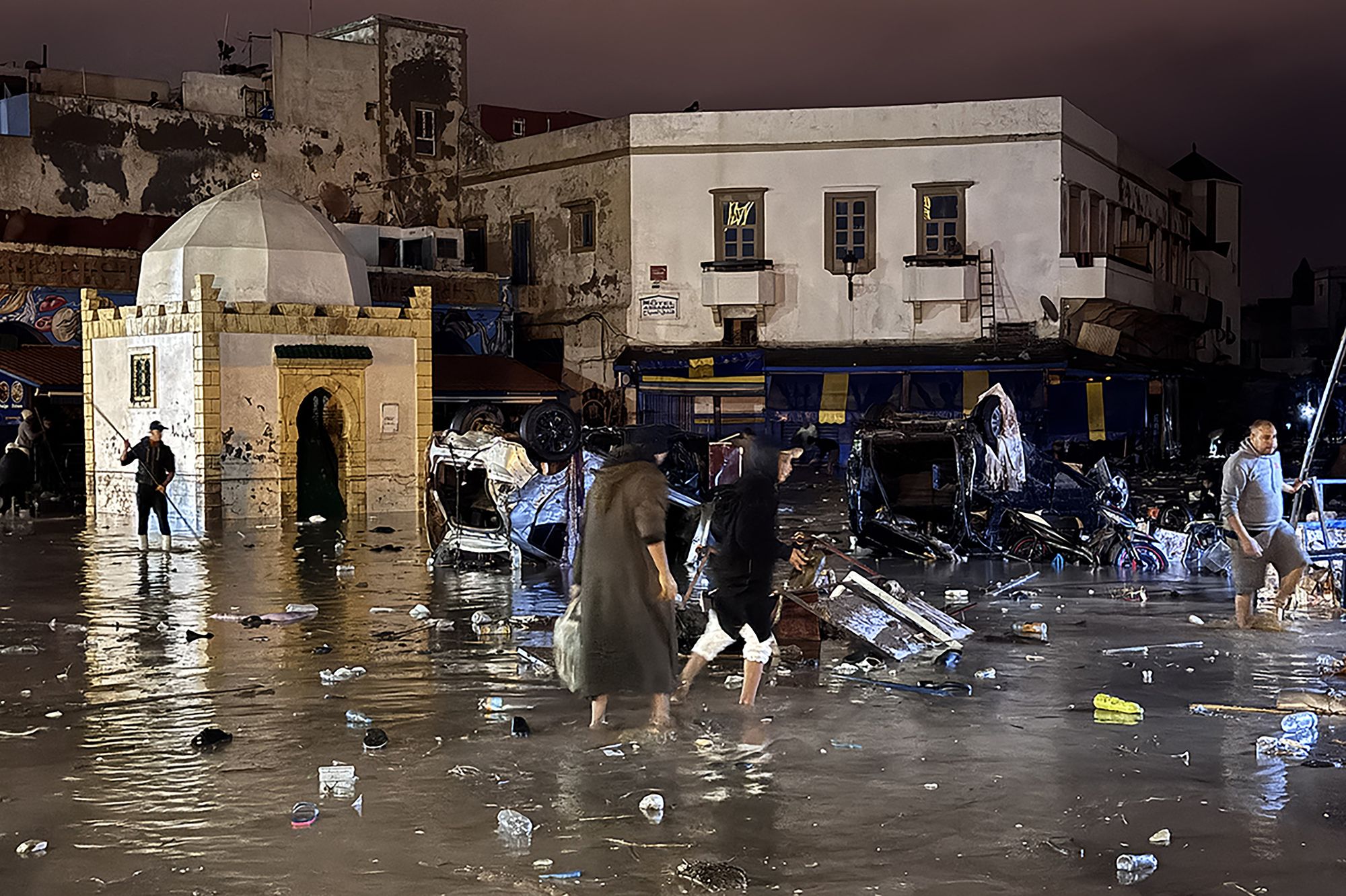 People wade through a square after a flash flood in Safi on December 14, 2025