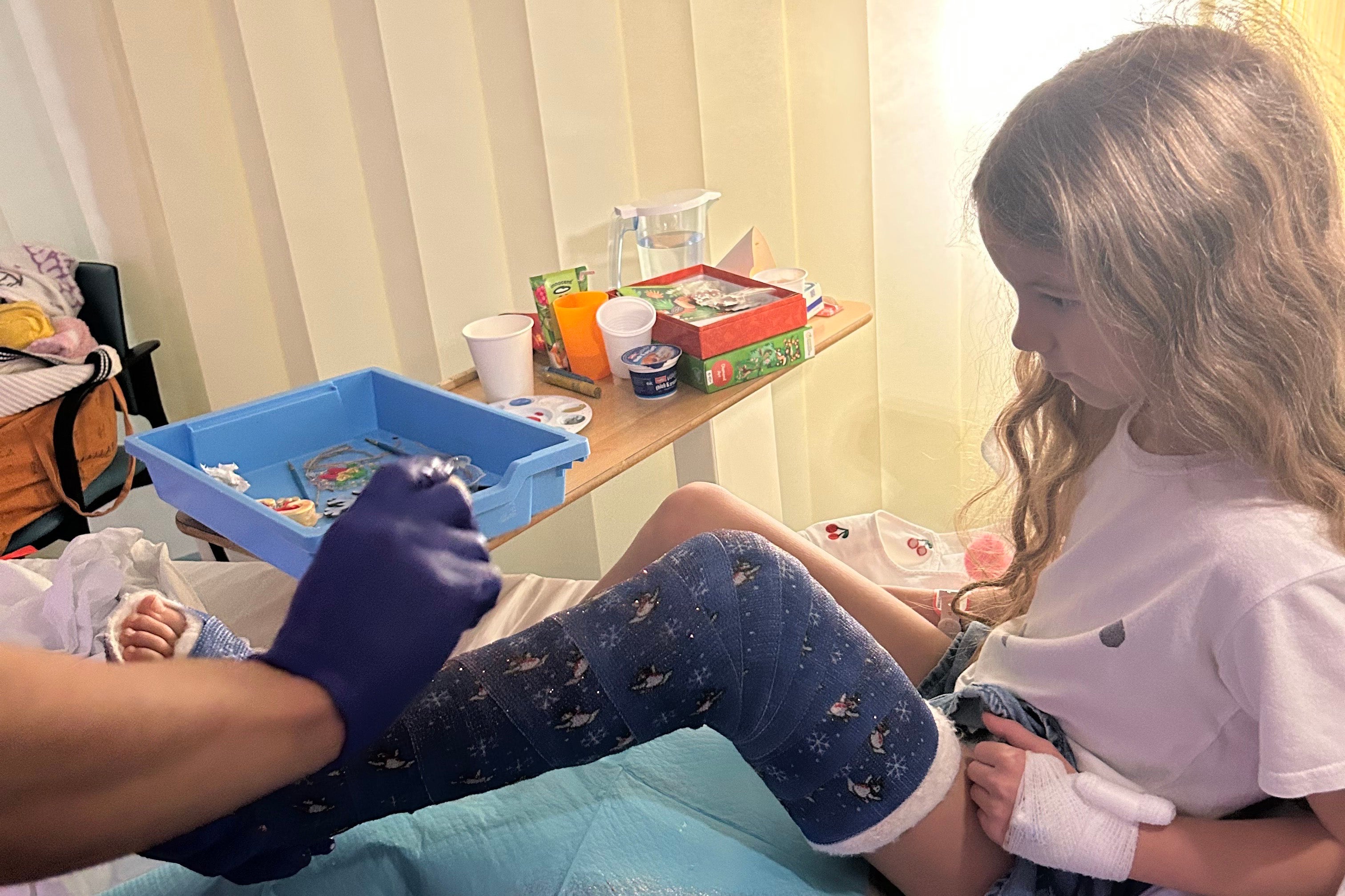 The doctor sprinkling gold glitter on Liberty’s snowman design leg cast