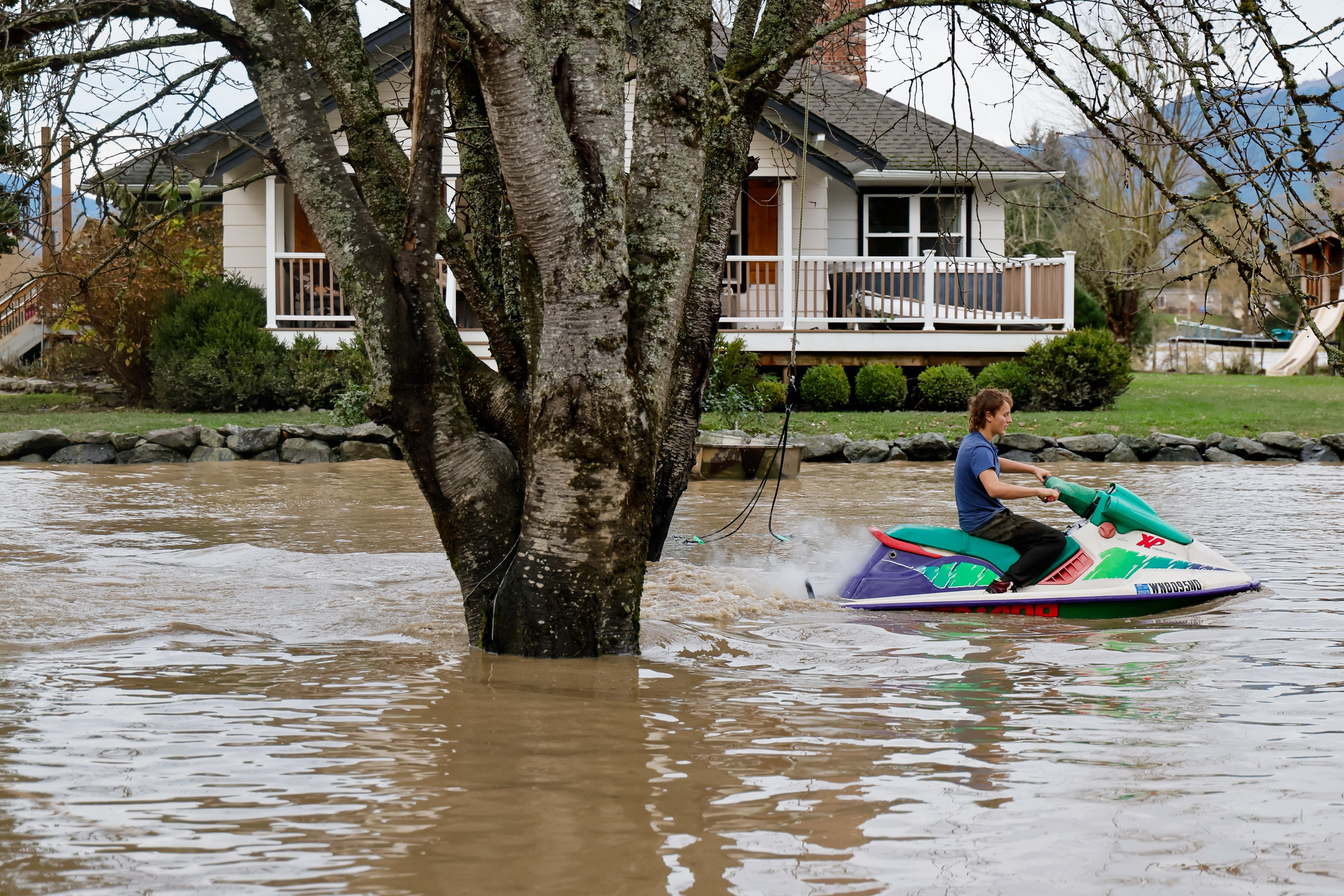 Justus Top, 13, rides a jet ski through his family's front yard Saturday, Dec. 13, 2025 in Sedro-Wooley, Wash. Water from the nearby Skagit River flooded the garage but spared the house, coming within a foot of the structure
