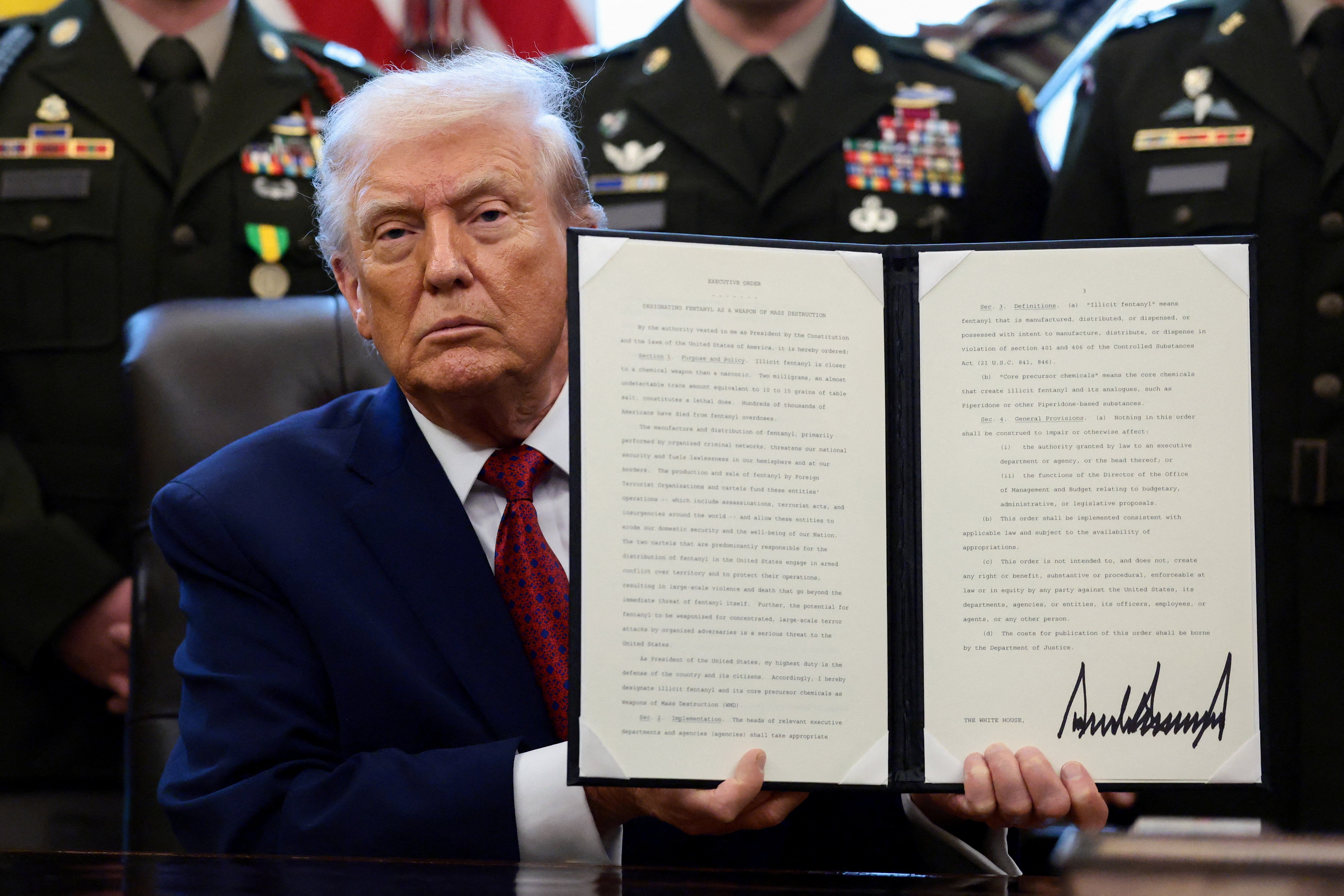 President Donald Trump shows a signed executive order classifying fentanyl as 'weapon of mass destruction' during an Oval Office event.