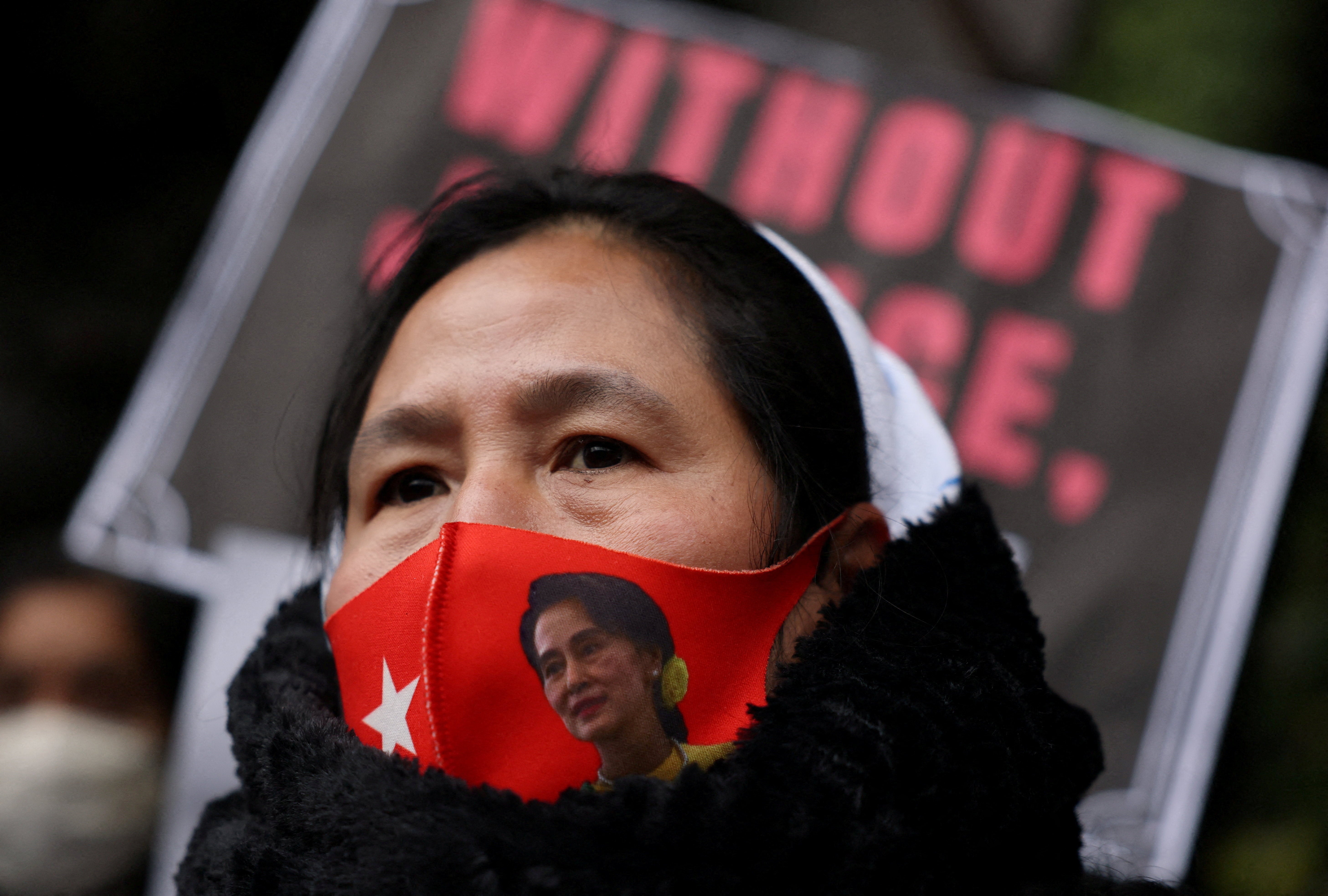 A protester wears a mask bearing the image of Suu Kyi