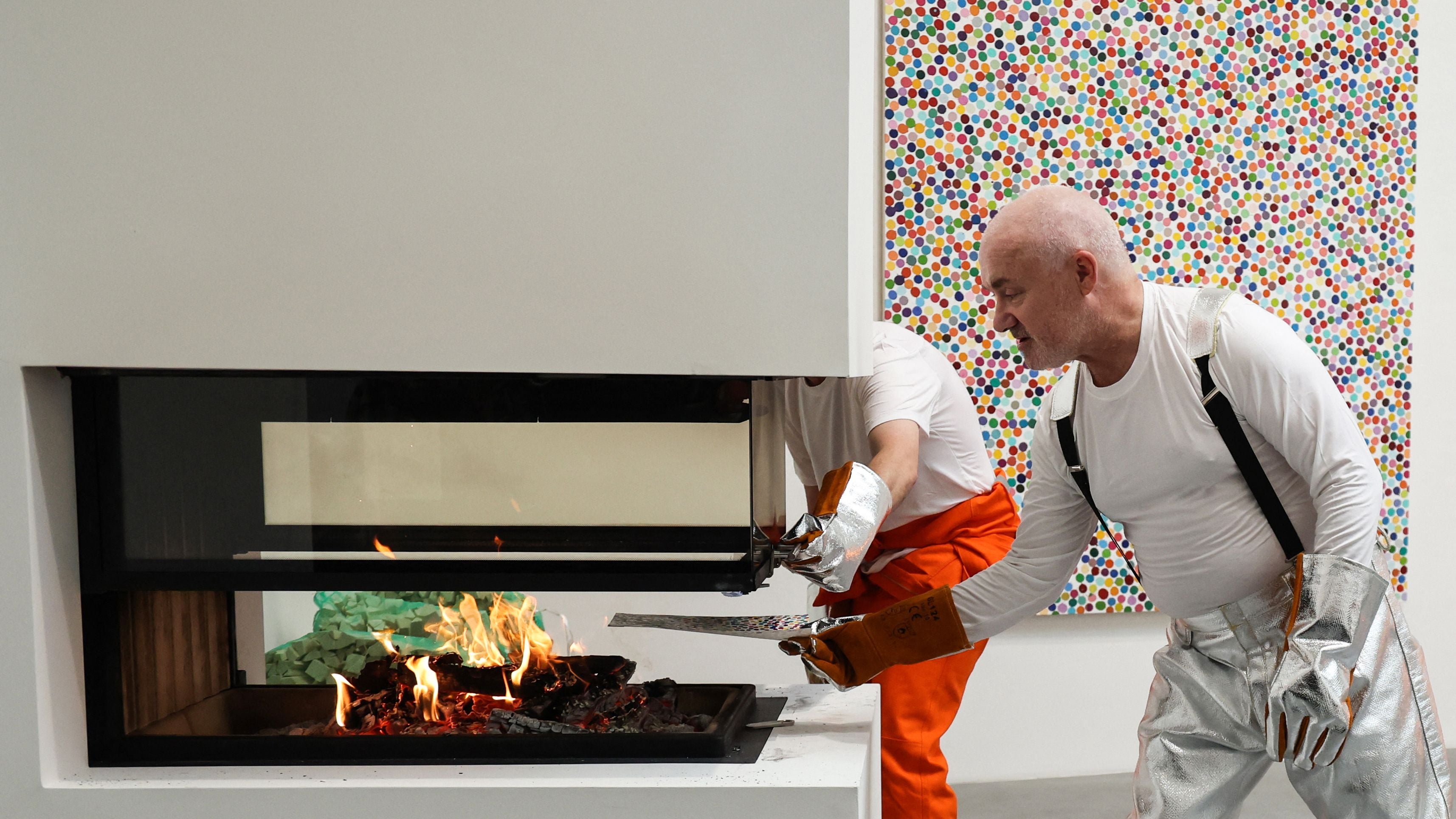 <p>British artist Damien Hirst burns an art piece at London's Newport Street Gallery in October 2022 as part of his exhibition 'The Currency'. The concept: after selling NFTs for thousands of his paintings, he then methodically burned the originals.</p>