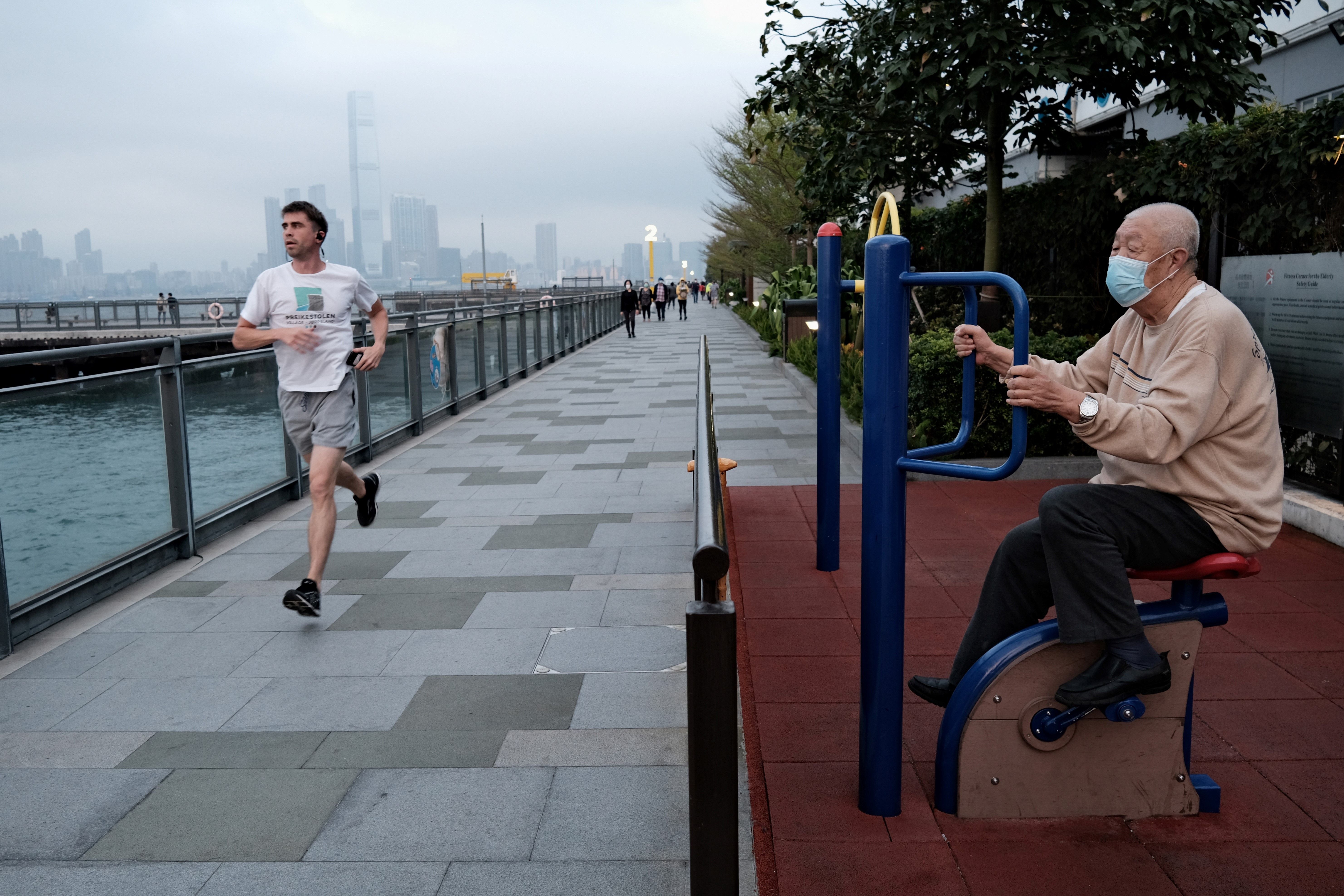 Elderly man exercises while another man jogs past him