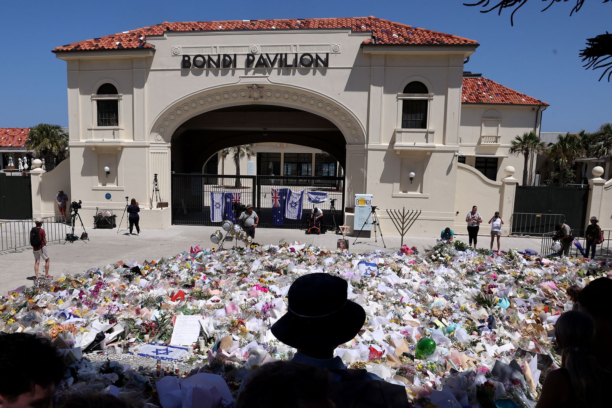Mourners stand near tributes for the victims of the Bondi Beach shooting