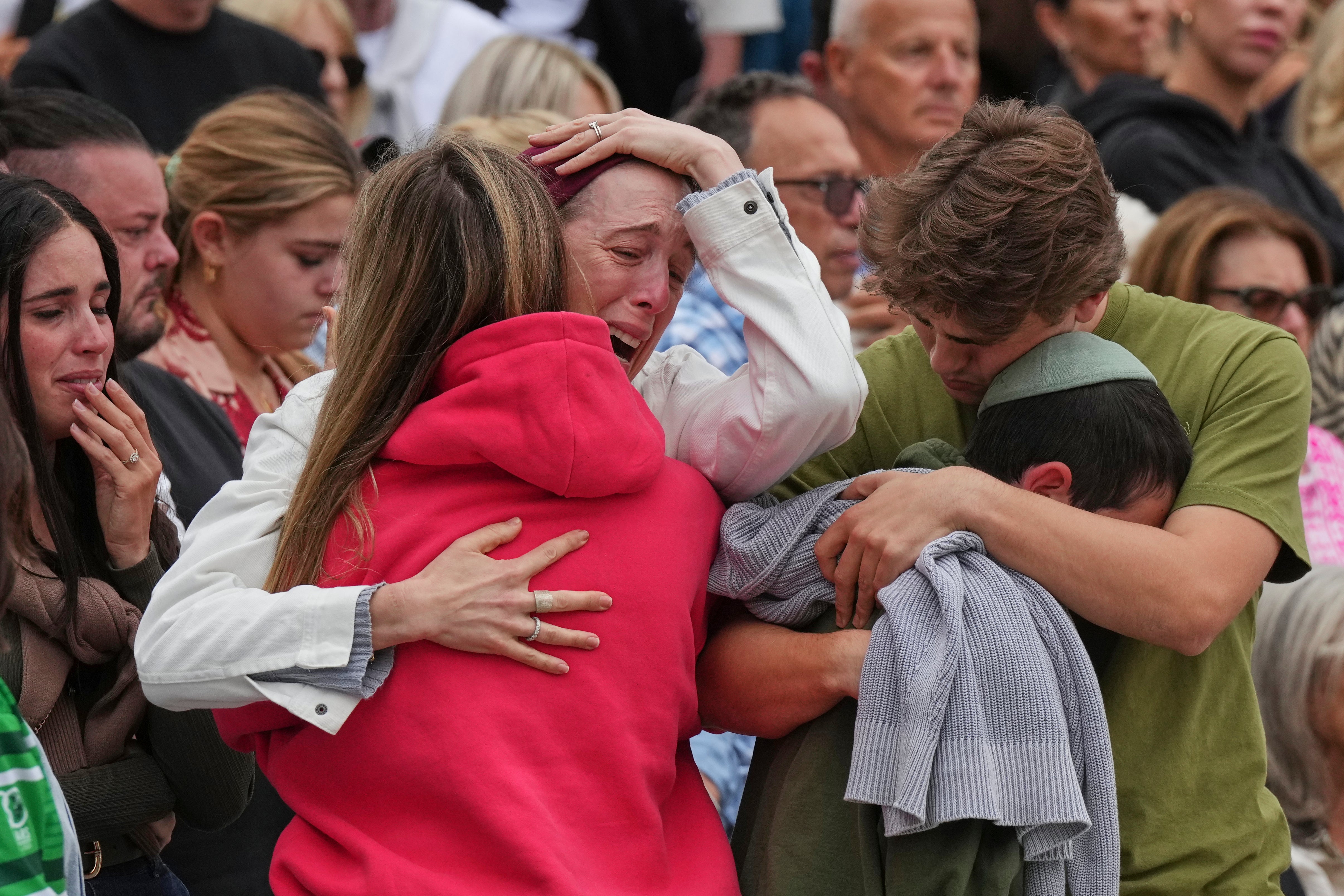 A family reacts near a floral memorial for victims of the Bondi attack in Sydney