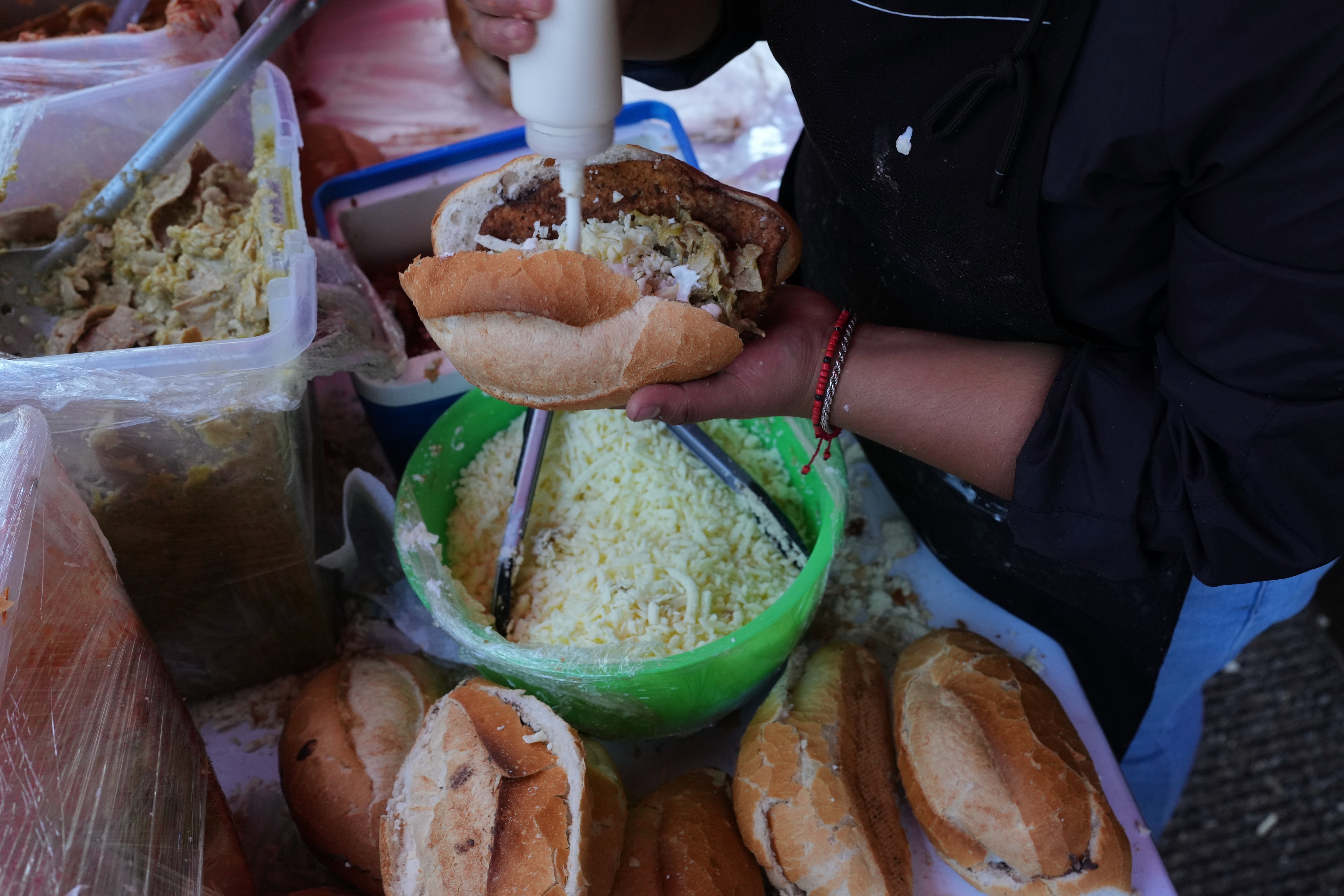 A vendor prepares a bolillo, a traditional Mexican bread, for consumption at a street stand in Mexico City.
