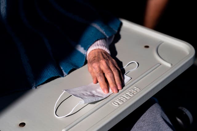 <p>An elderly resident puts her hand on a face mask </p>