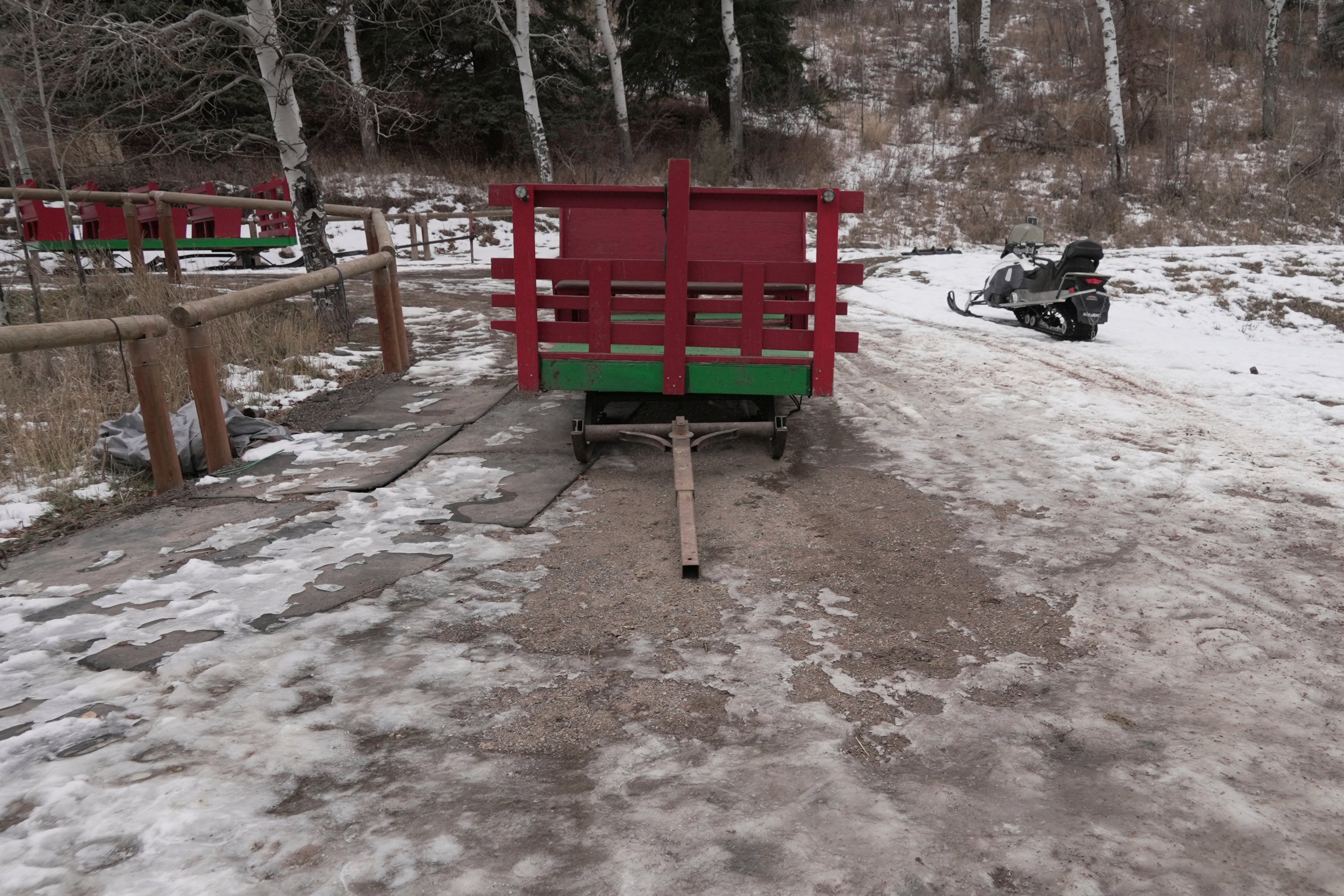 A sleigh rests by a stable, unable to be used with minimal snow cover