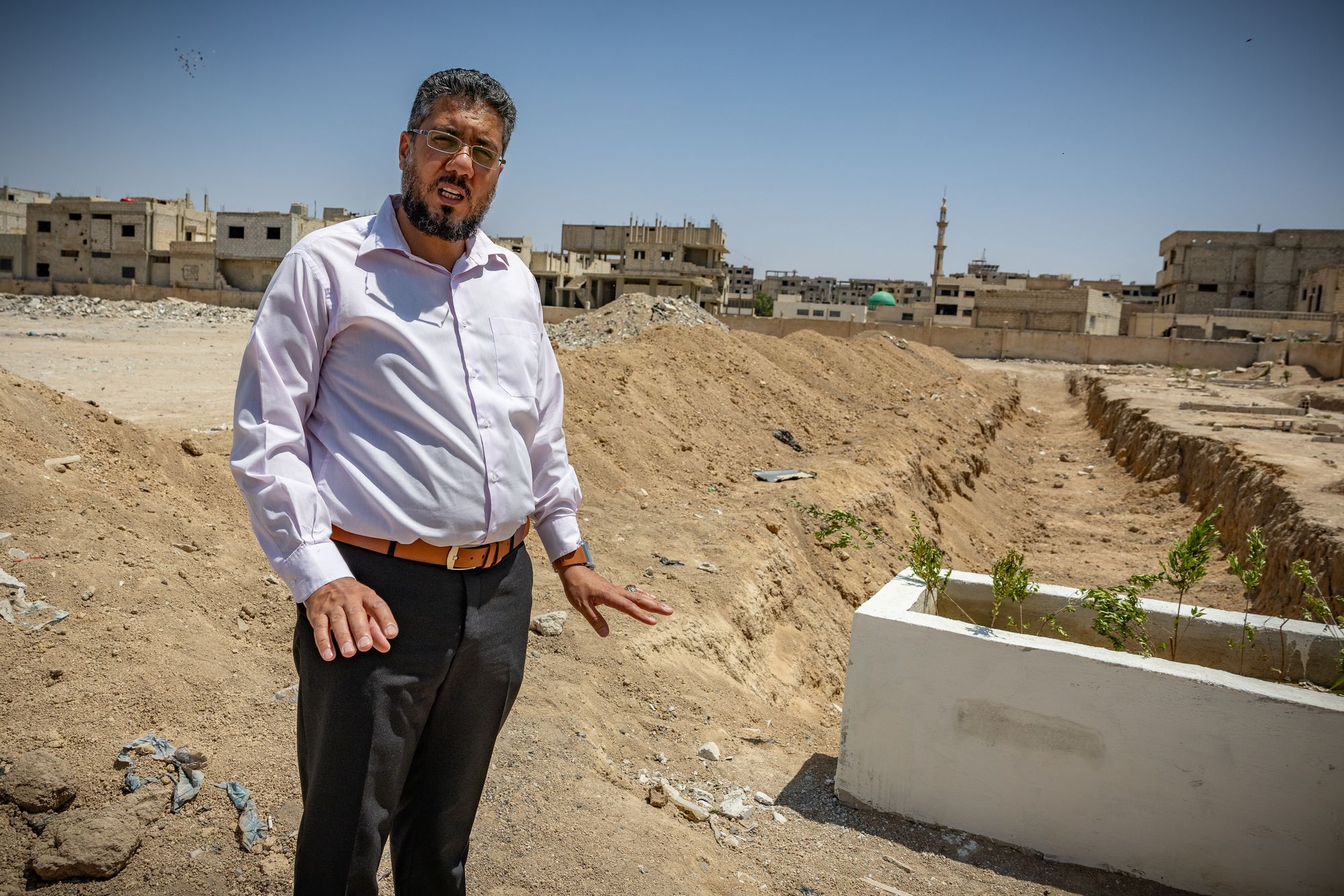 Hamza by the grave they hand dug to rebury bodies found southeast of Damascus