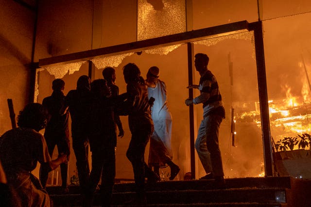 <p>People are seen at the entrance to the Daily Star building as it burns in Dhaka on 19 December 2025</p>