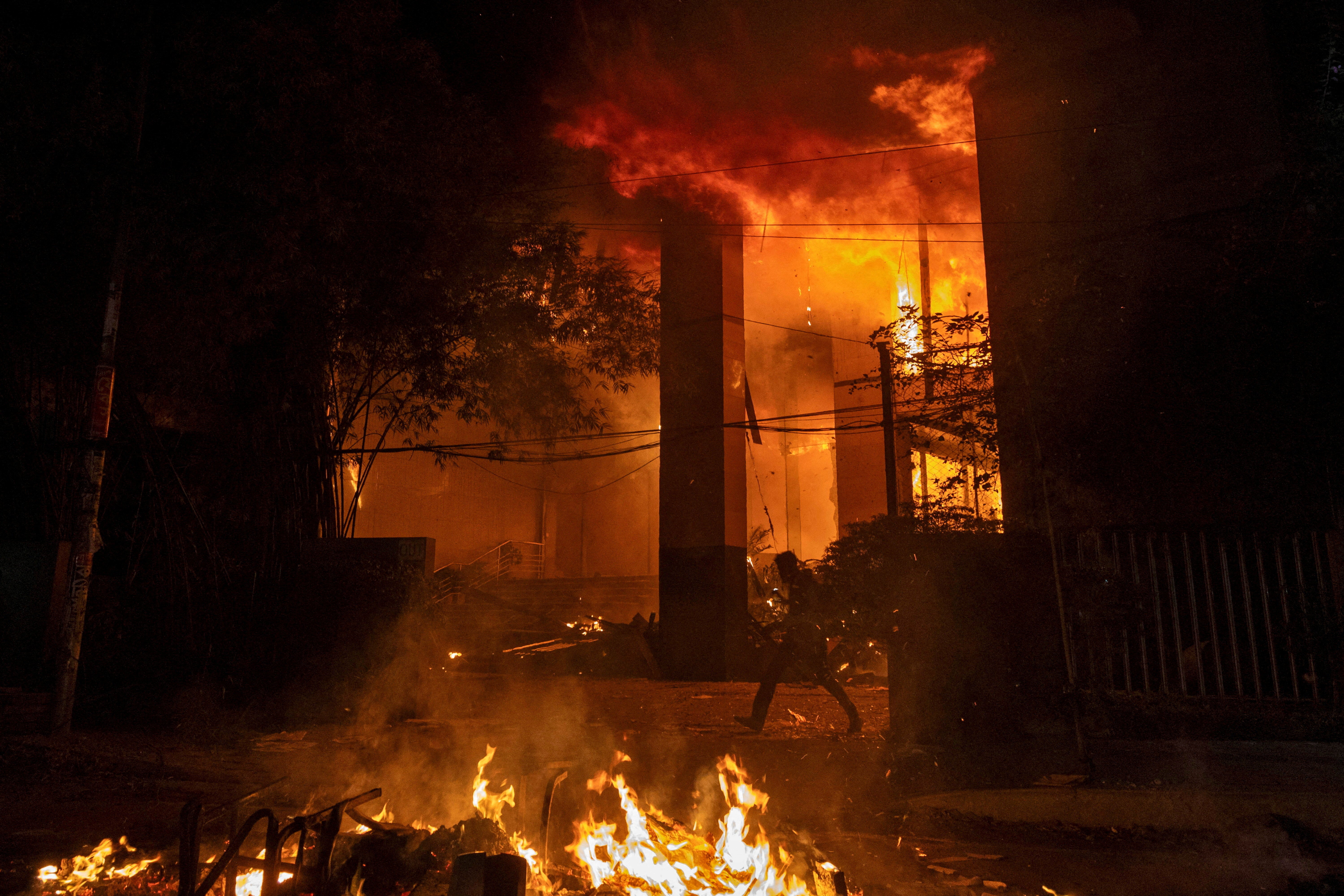 A man walks after a group of people set fire to The Daily Star newspaper office building following the death of Sharif Osman Hadi, in Dhaka