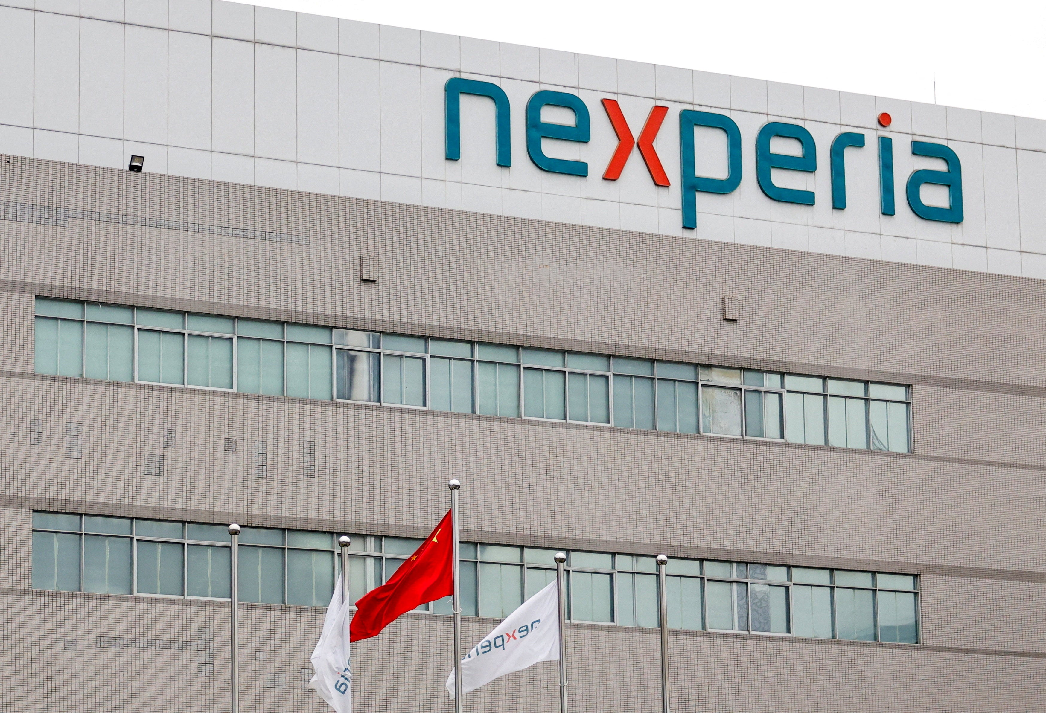 Flags fly next to a logo of Nexperia at the facade of its factory amidst a shortage of chip supply caused by a diplomatic standoff between China and Netherlands over the company, in Dongguan, Guangdong province, China