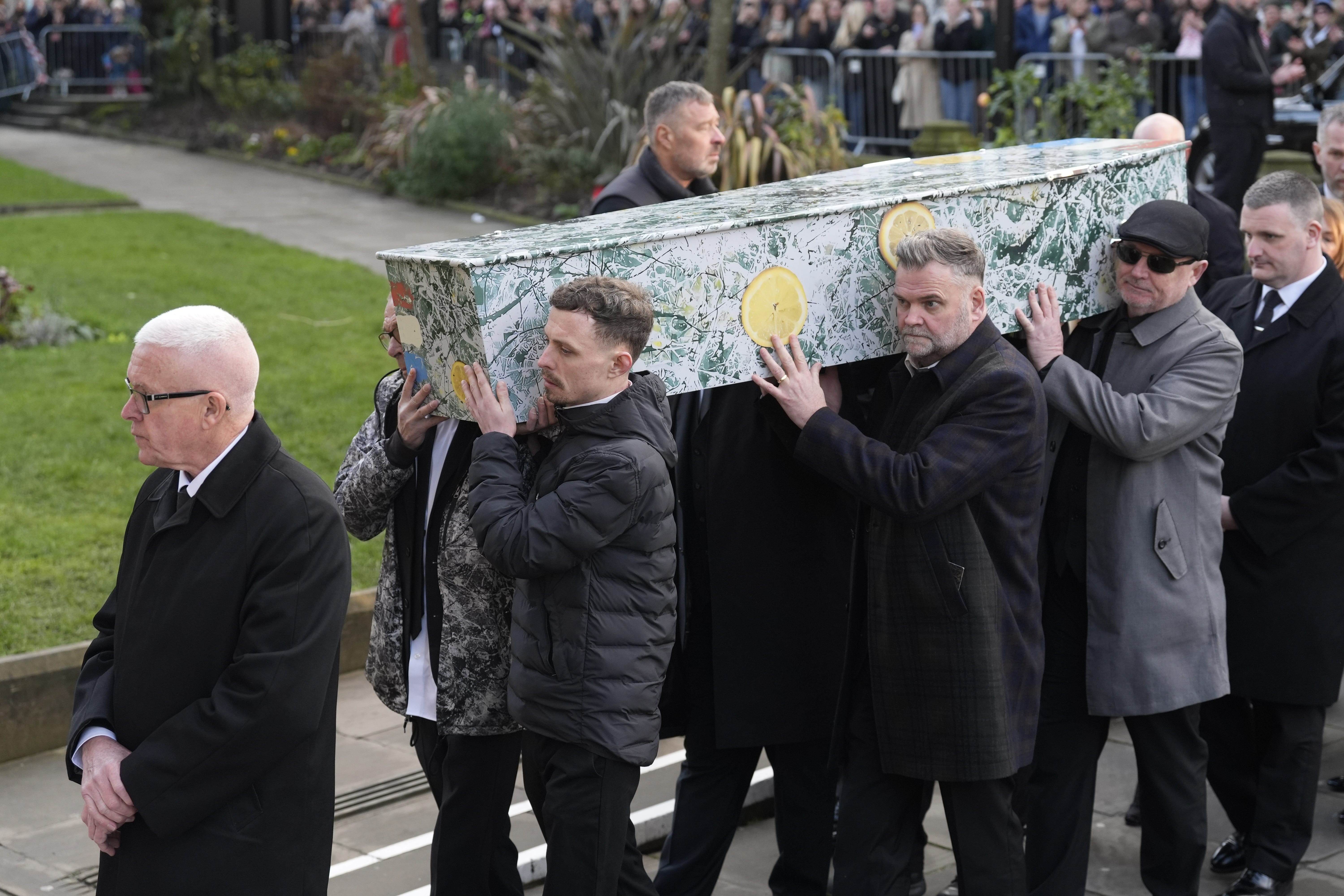 <p>The bearer party carry the coffin decorated in the artwork Bye Bye, Badman painted by John Squire for the cover of the Stone Roses debut album.</p>