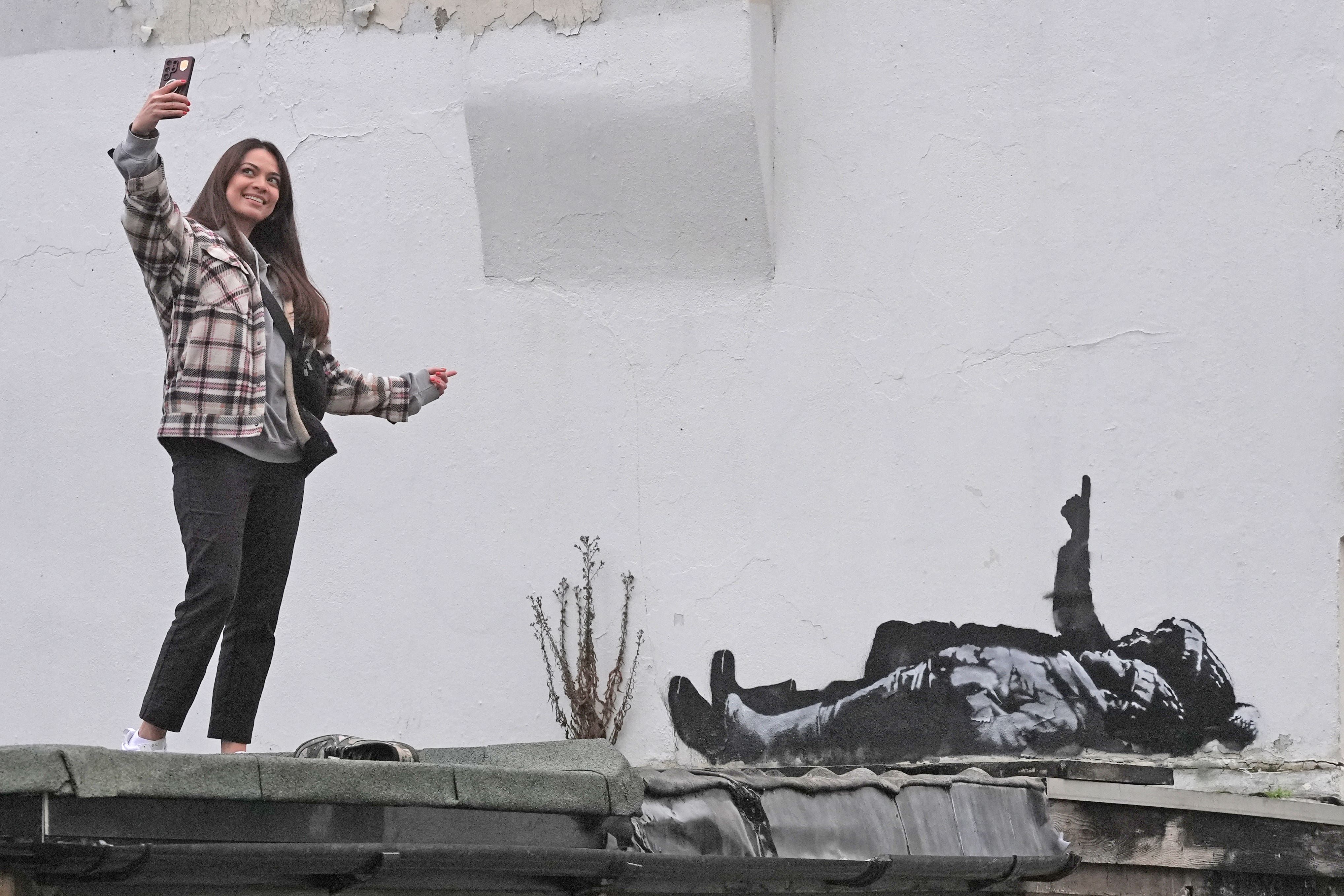A person takes a selfie with a piece of the Banksy artwork in Bayswater (Stefan Rousseau/PA)