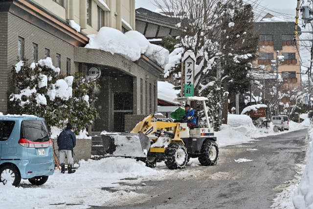 <p>A man using heavy machinery to clear snow from a street in the ski resort town of Hakuba, Nagano prefecture</p>