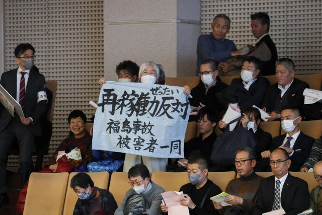 <p>A woman holds a banner that reads, "Against Restart" near auditors seated on the day Niigata Prefectural Assembly lawmakers take part in a vote of confidence </p>