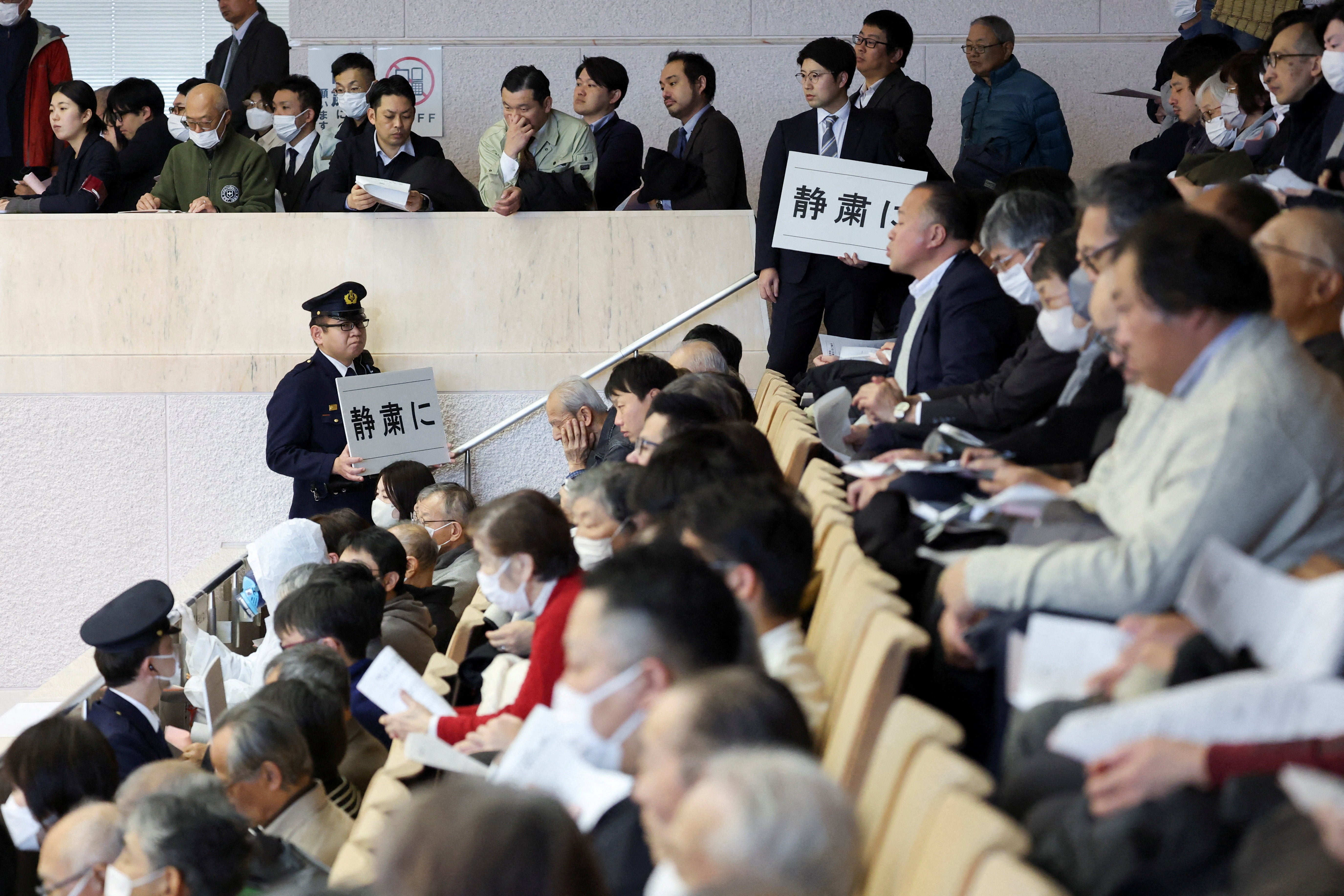 Security officers hold placards that reads, "Silence please" near auditors seated as Niigata Prefectural Assembly lawmakers take part in a vote of confidence in the prefectural governor's decisions on a partial restart of the Tokyo Electric Power Company's (TEPCO) Kashiwazaki Kariwa Nuclear Power Plant