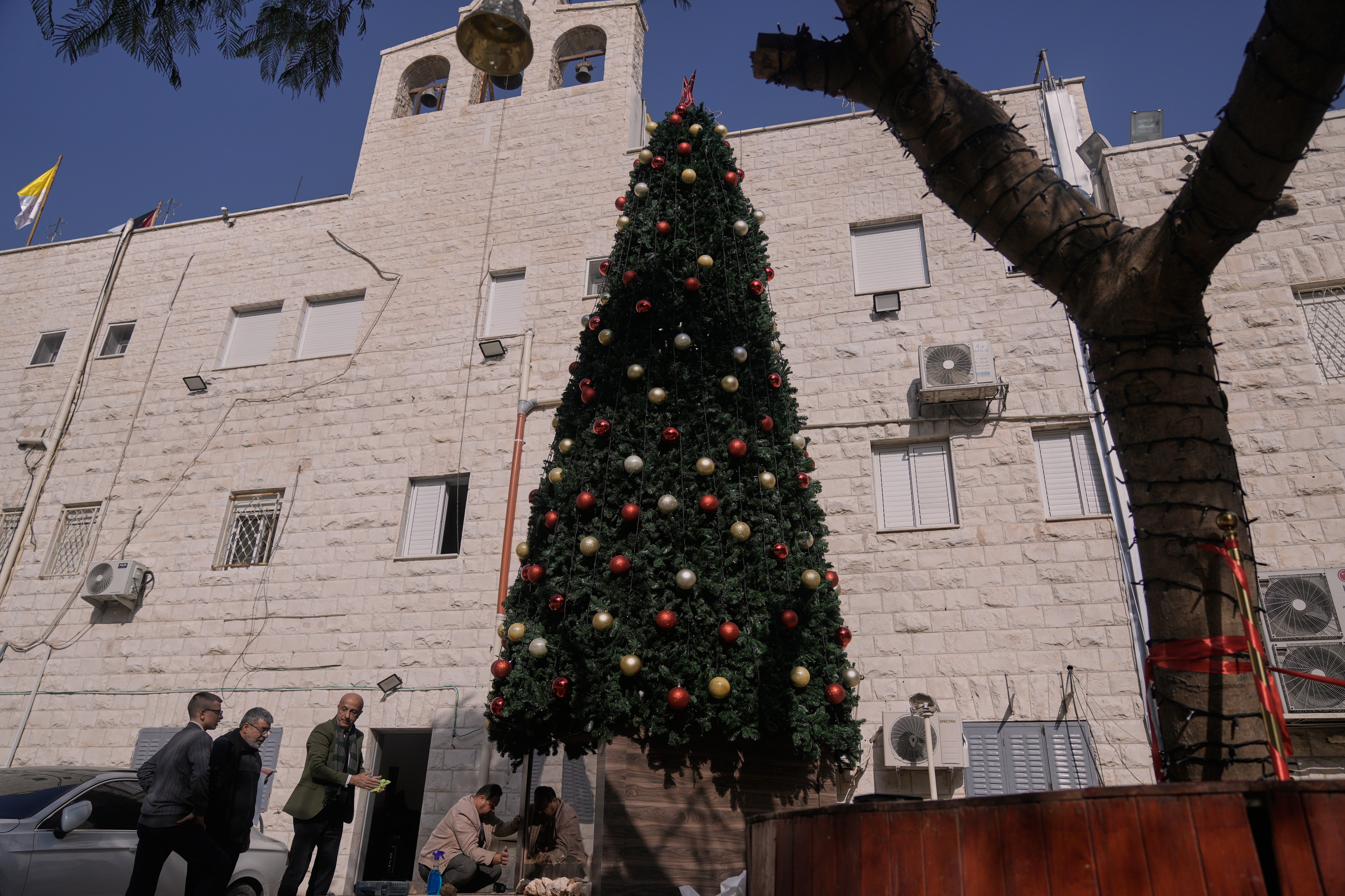 Palestinian parishioners check a recently installed Christmas tree after the previous one was destroyed at the Holy Redeemer Latin Church in the West Bank town of Jenin