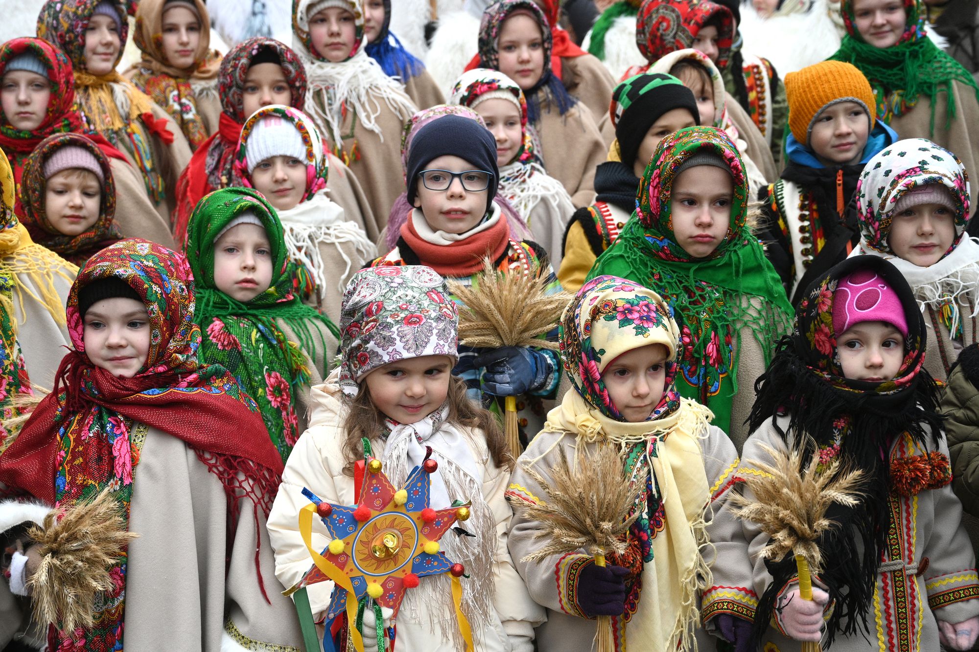 Children wearing traditional clothes and carrying Ukrainian traditional 'Didukh' decorations take part in a Christmas Eve procession in Lviv
