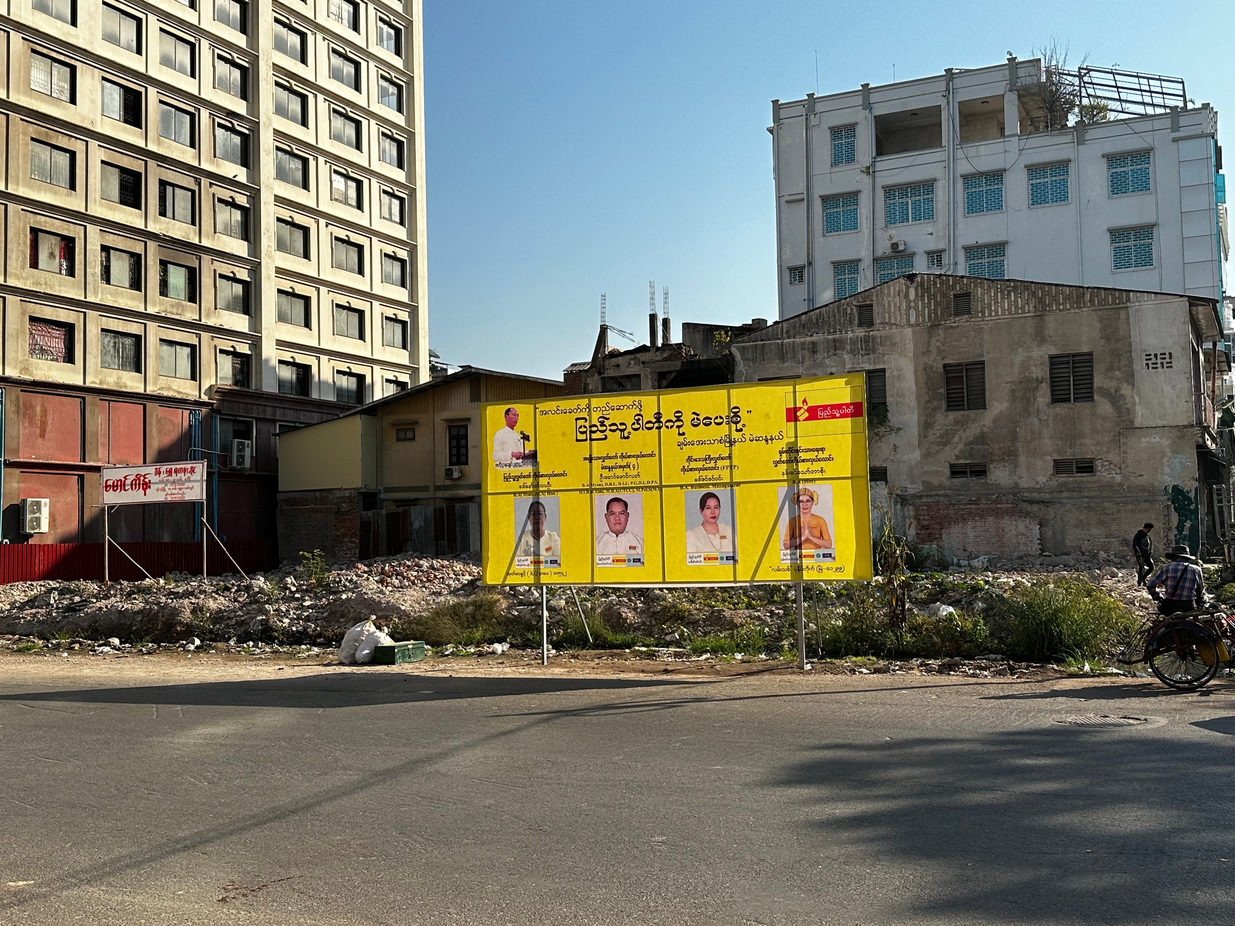 An election sign in front of a pile of rubble in Mandalay, Myanmar