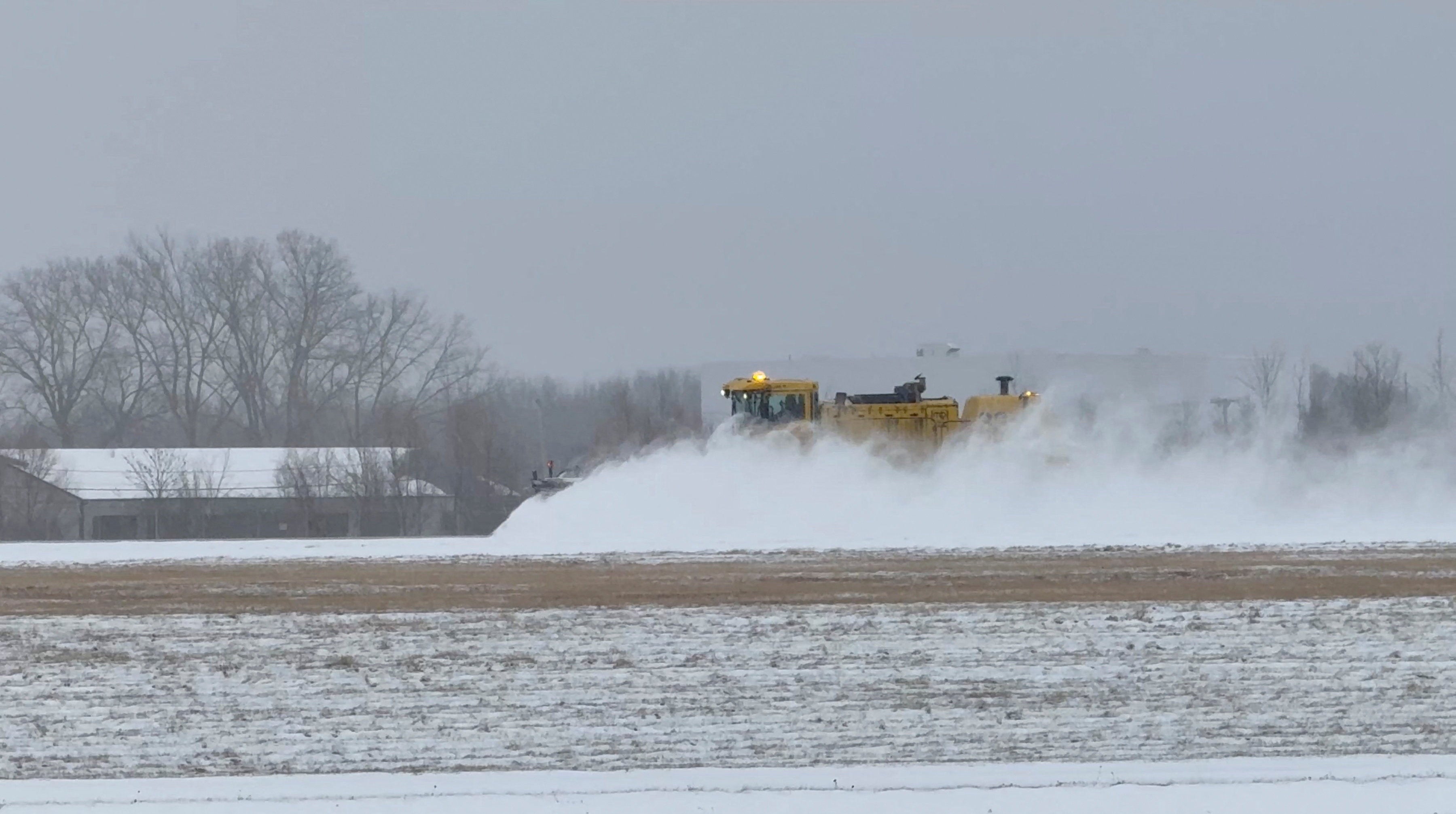 A vehicle clears snow during a winter storm at Greater Rochester International Airport