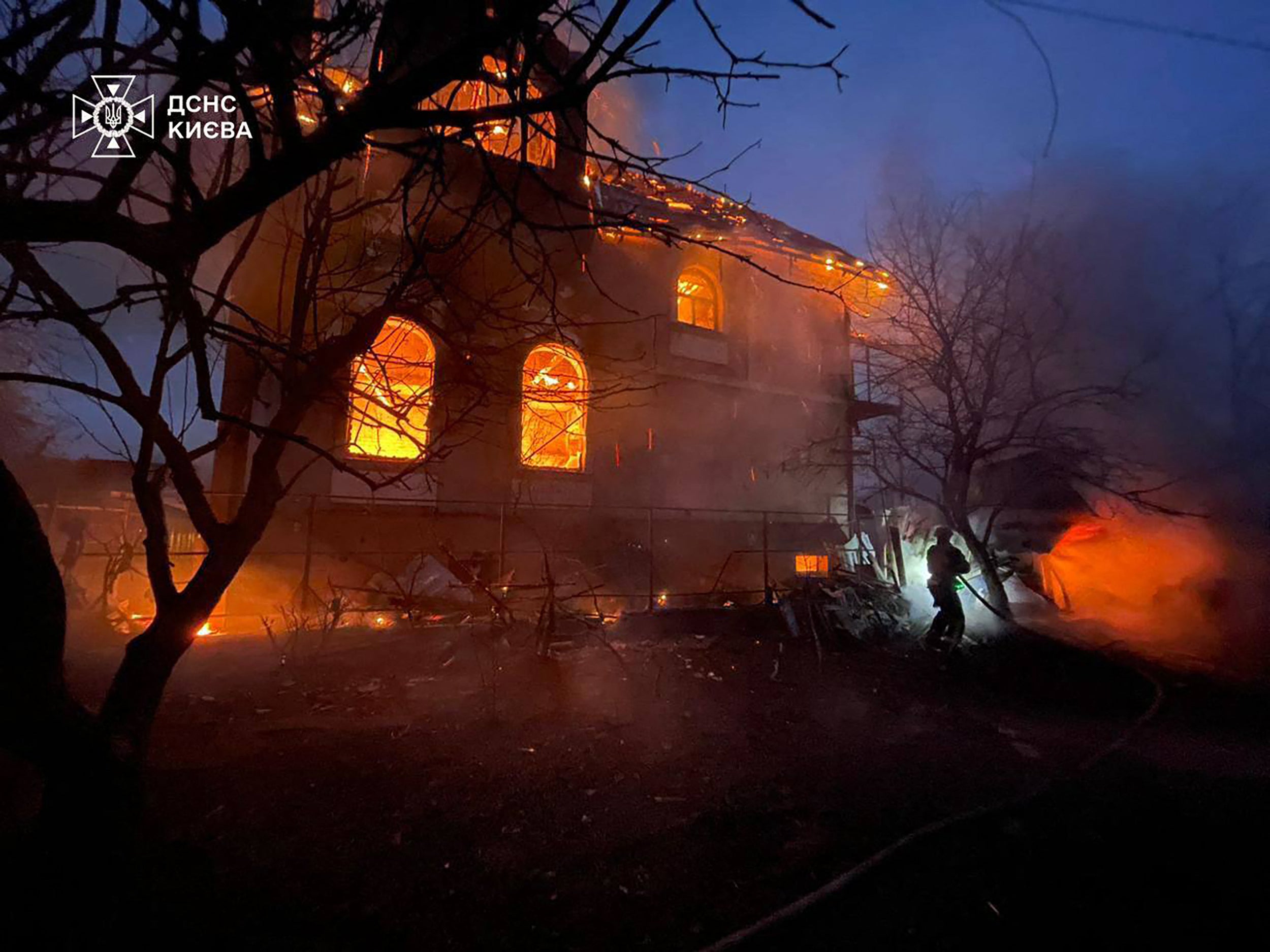 Ukrainian firefighters work on site to extinguish the fire of a building damaged during a Russian drone and missile attack in Kyiv