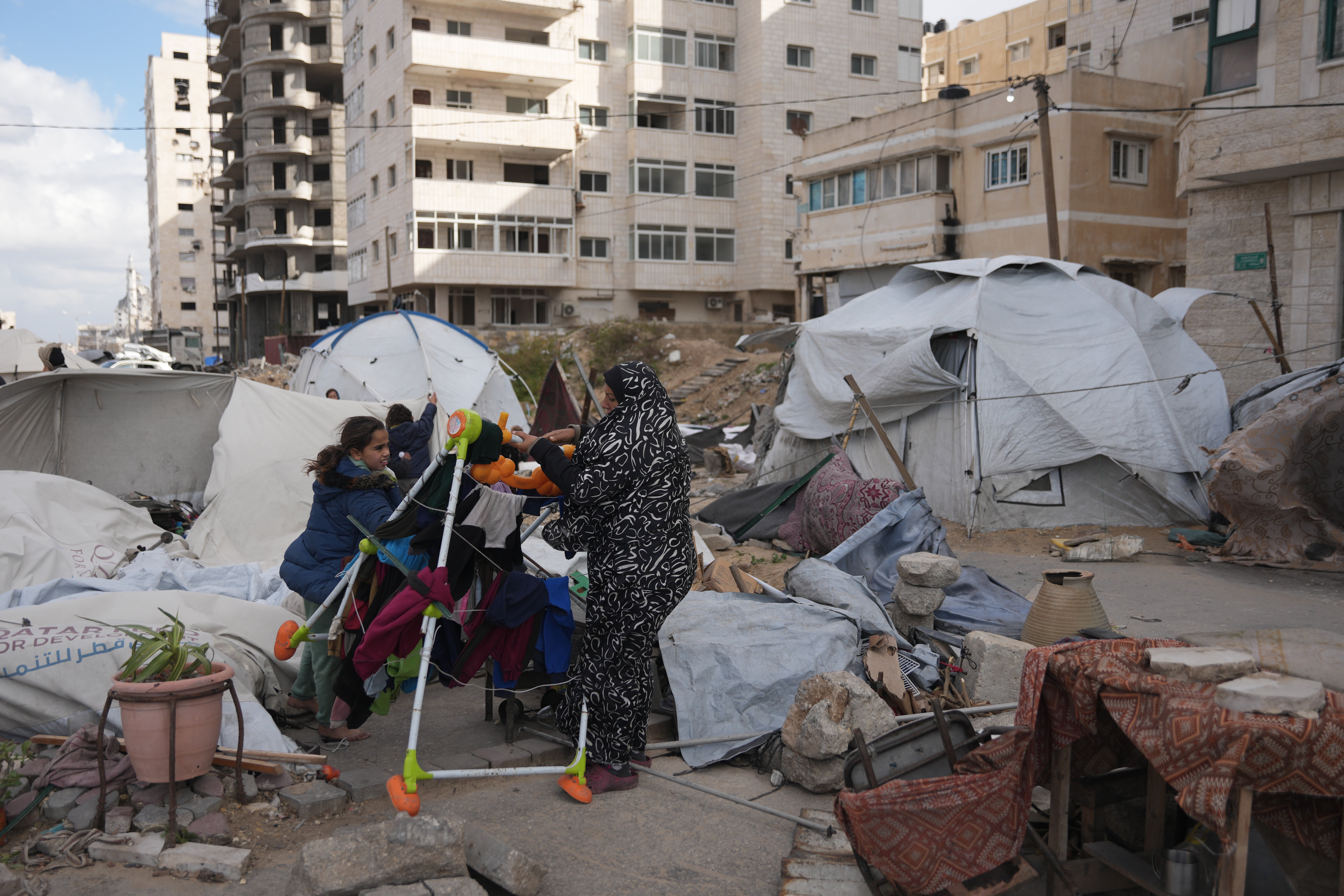 Members of a family stand by a tent destroyed by strong wind and rain in Gaza City
