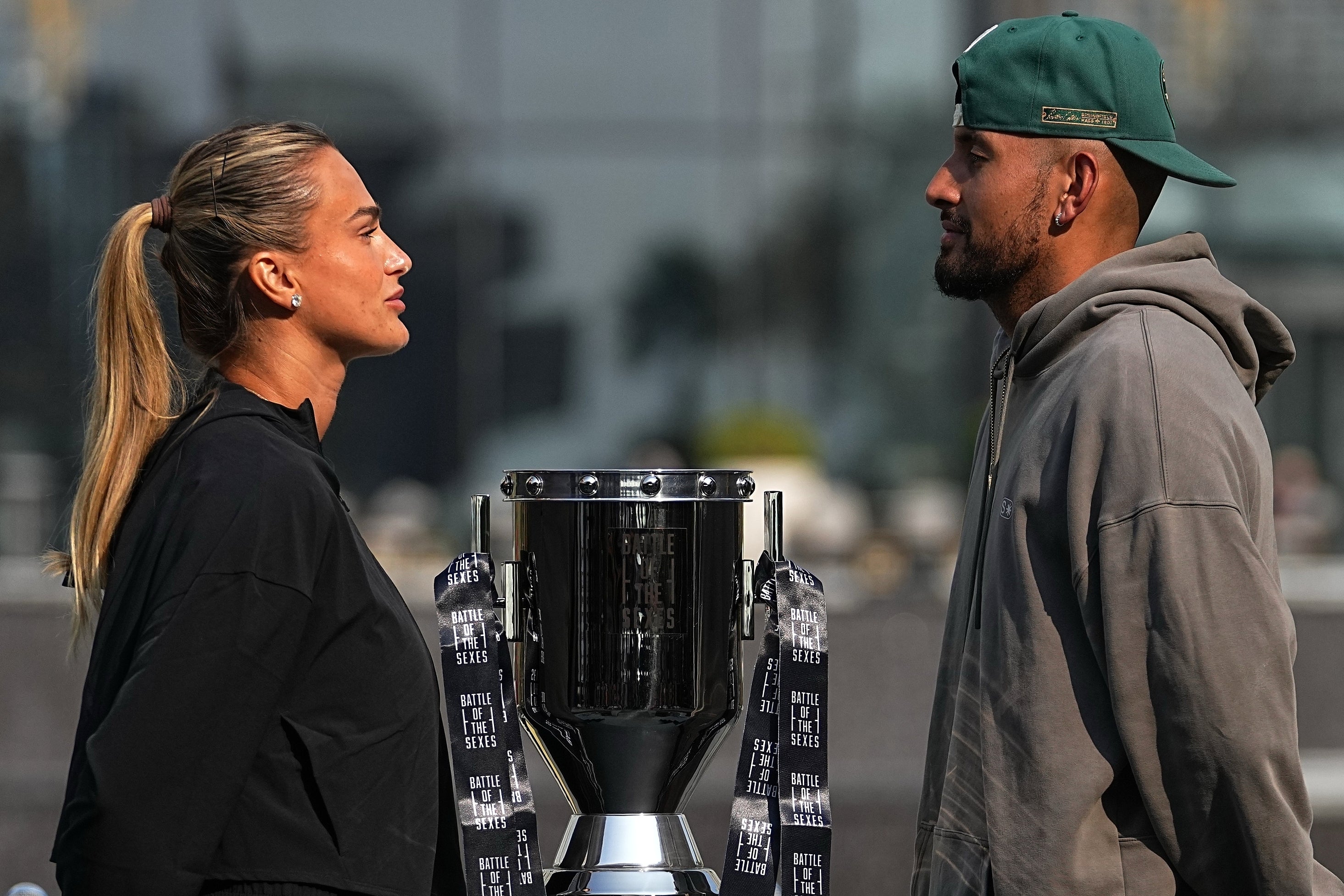 Tennis players Aryna Sabalenka of Belarus, left, and Nick Kyrgios of Australia face off with the trophy ahead of the Battle of the Sexes exhibition match