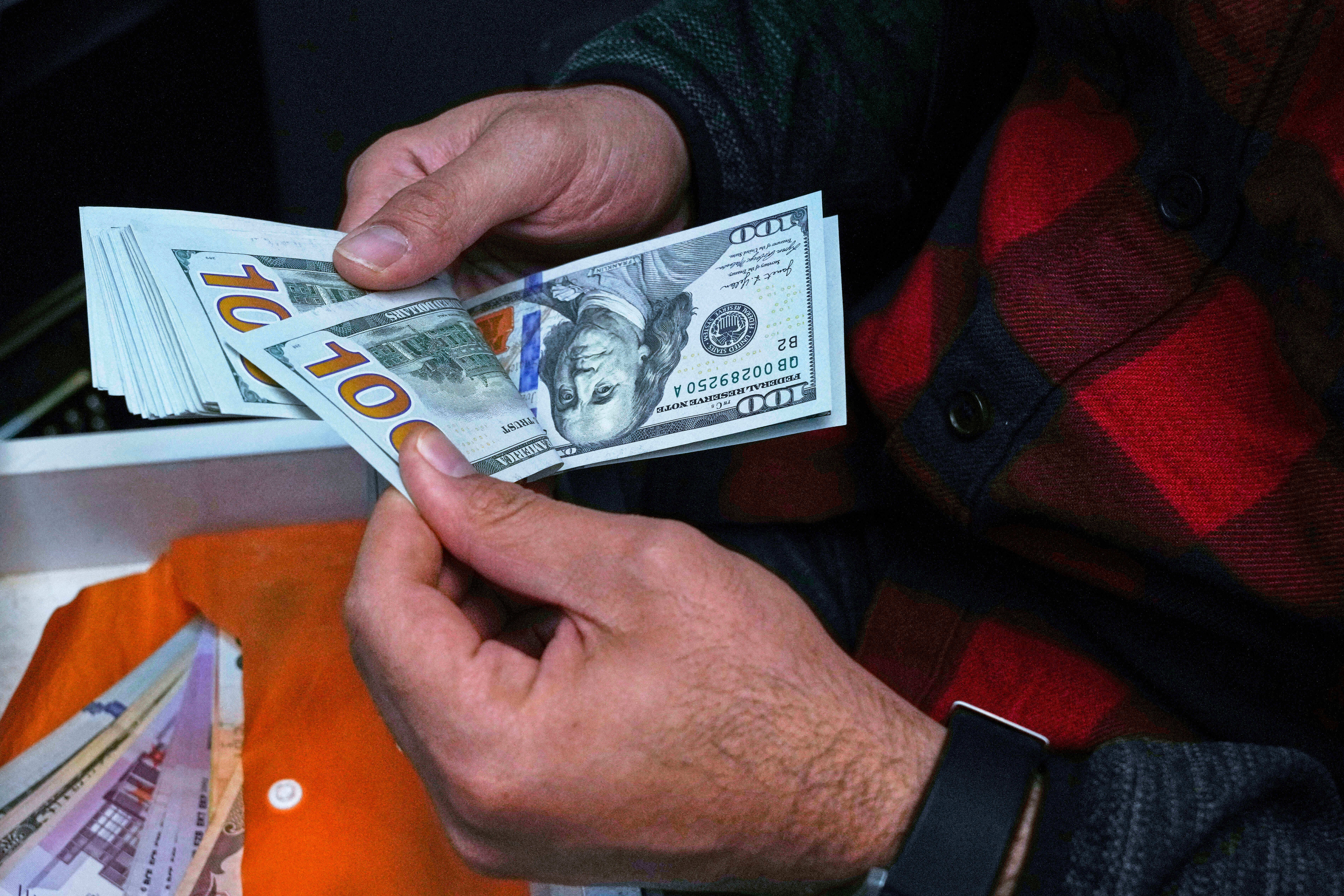 A currency exchange bureau worker counts U.S. dollars in Tehran