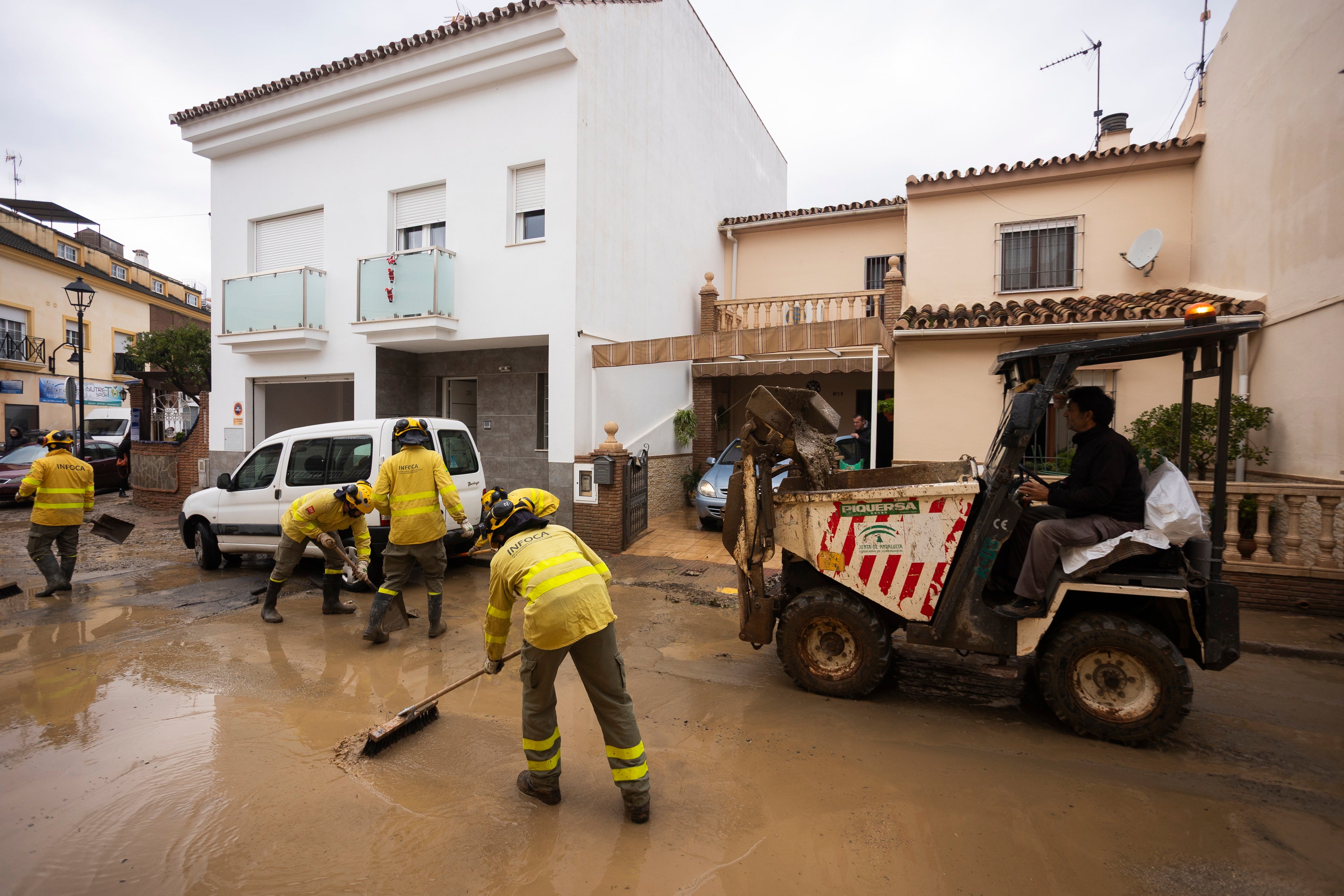 Members of the Andalusian regional forest firefighting unit remove mud from a street in Malaga, southern Spain