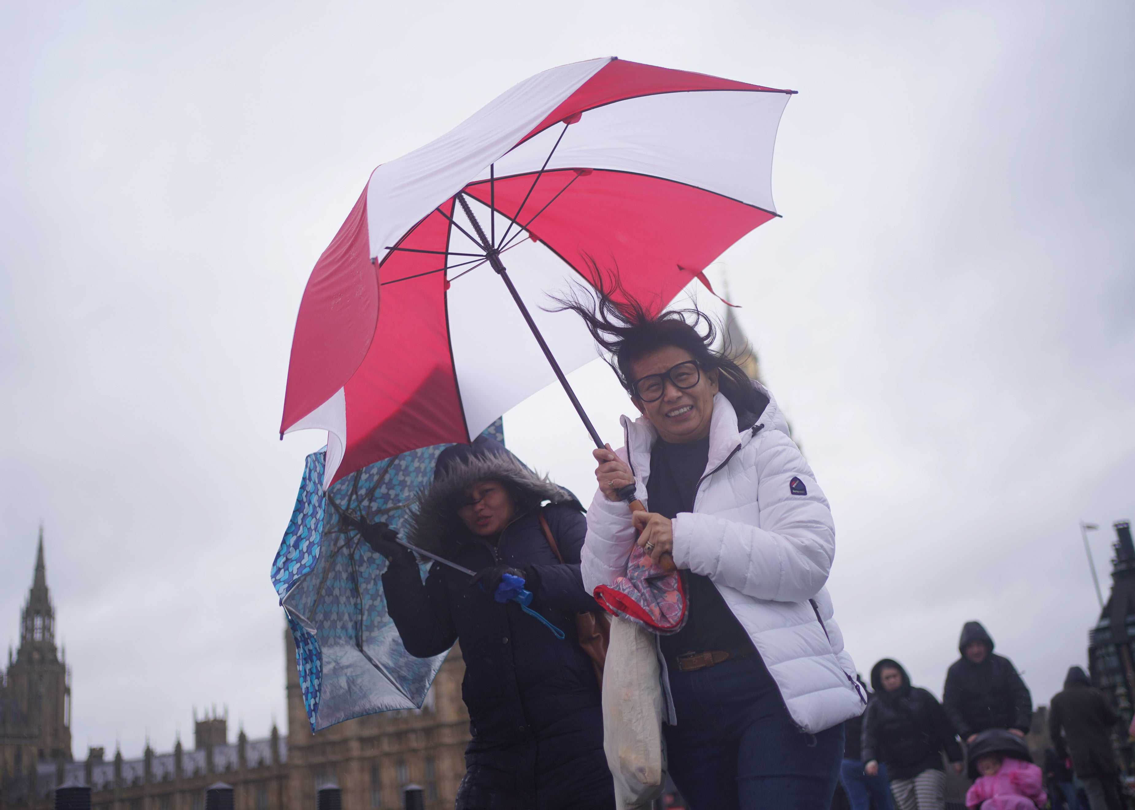 People walk in wind and rain on London’s Westminster Bridge