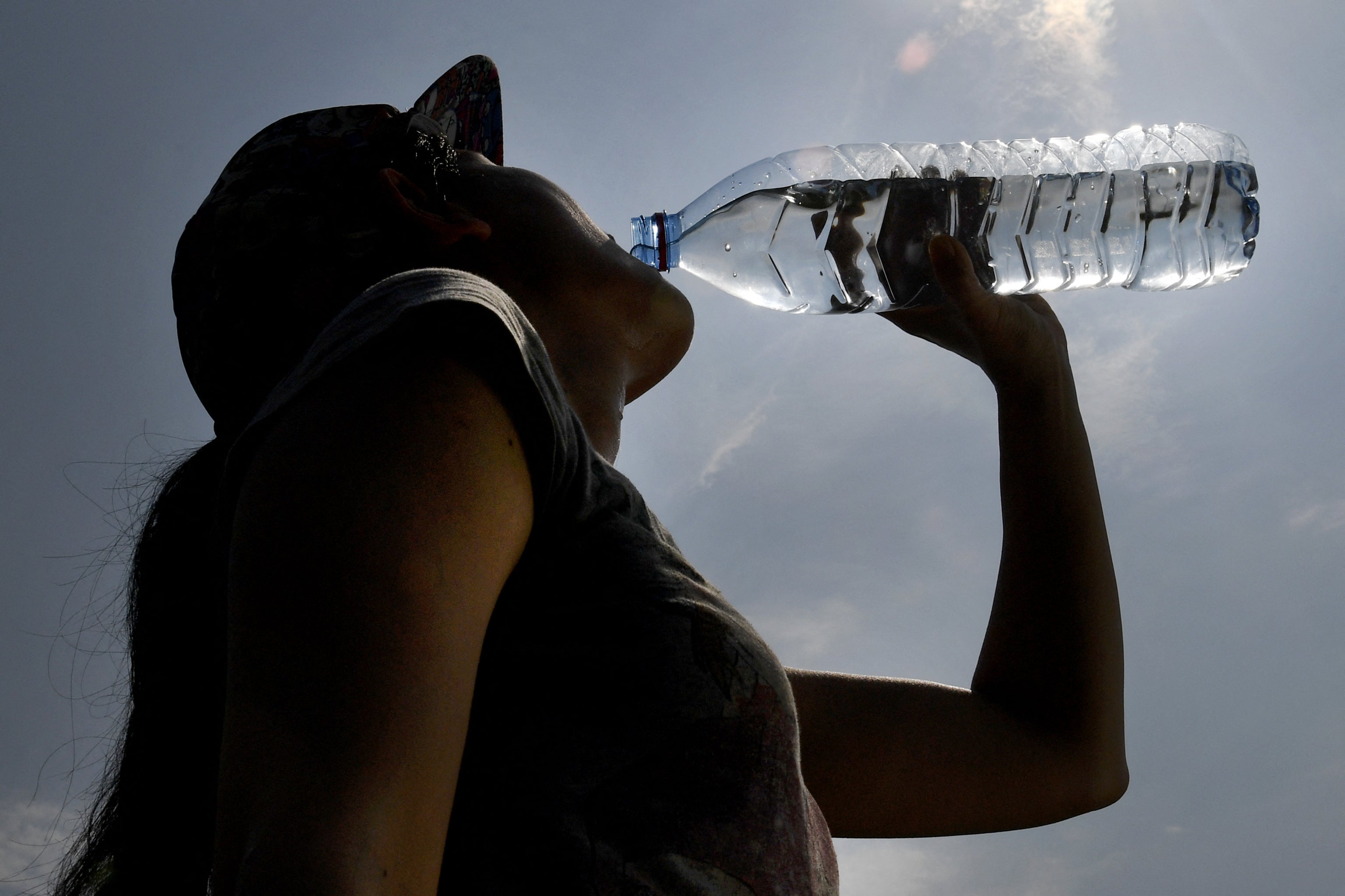 A woman drinks water from a plastic bottle