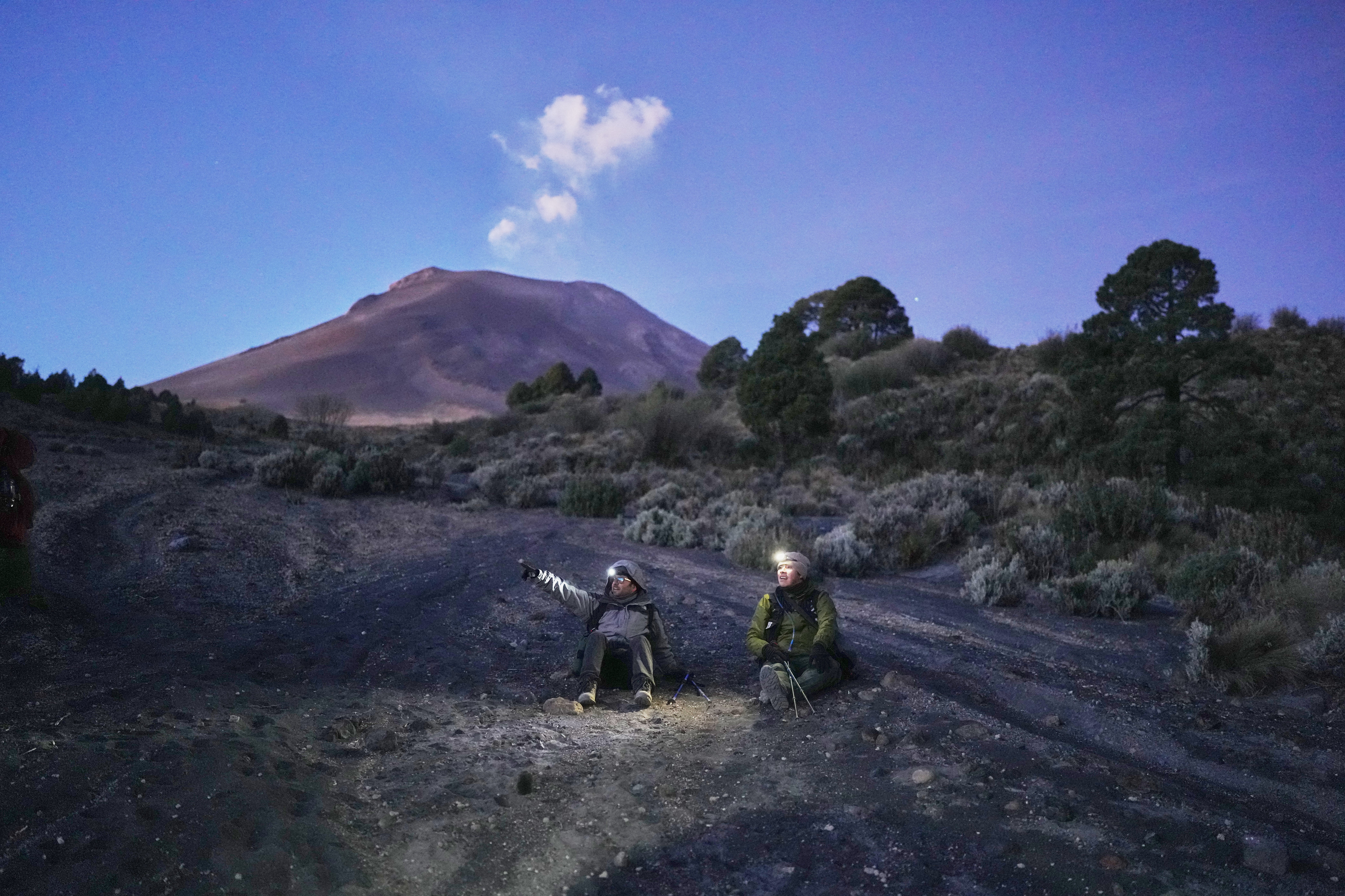 Marco Calo, left, a geophysicist at the National Autonomous University of Mexico (UNAM), take a break on the slopes of the Popocatepetl volcano in Mexico, Friday, Dec. 5, 2025. (AP Photo/Eduardo Verdugo)