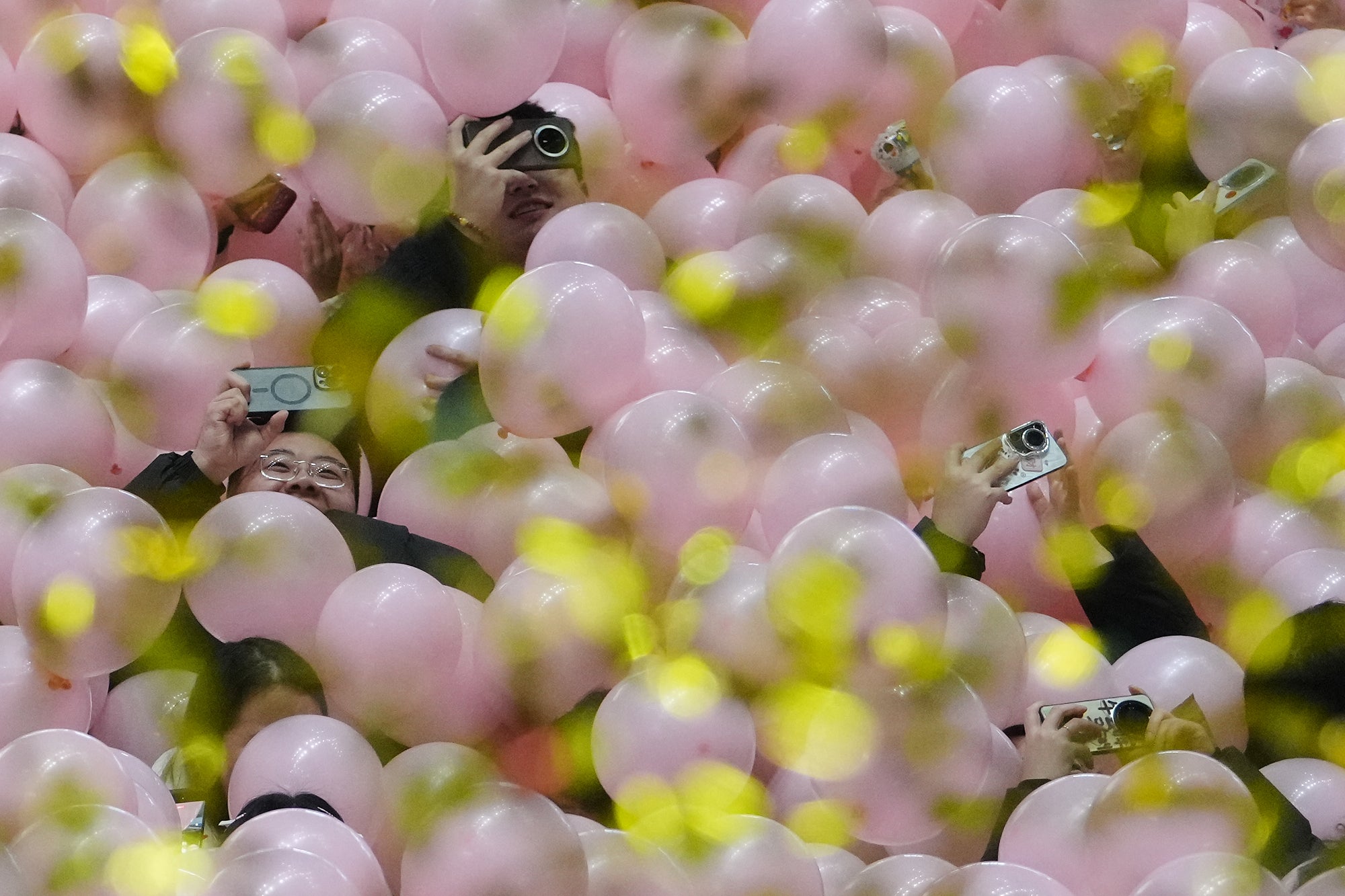 Revelers use their smartphones to film the falling balloons and confetti as they celebrate the start of 2026 during the New Year countdown event held at a shopping mall in Beijing, early Thursday, Jan. 1, 2026