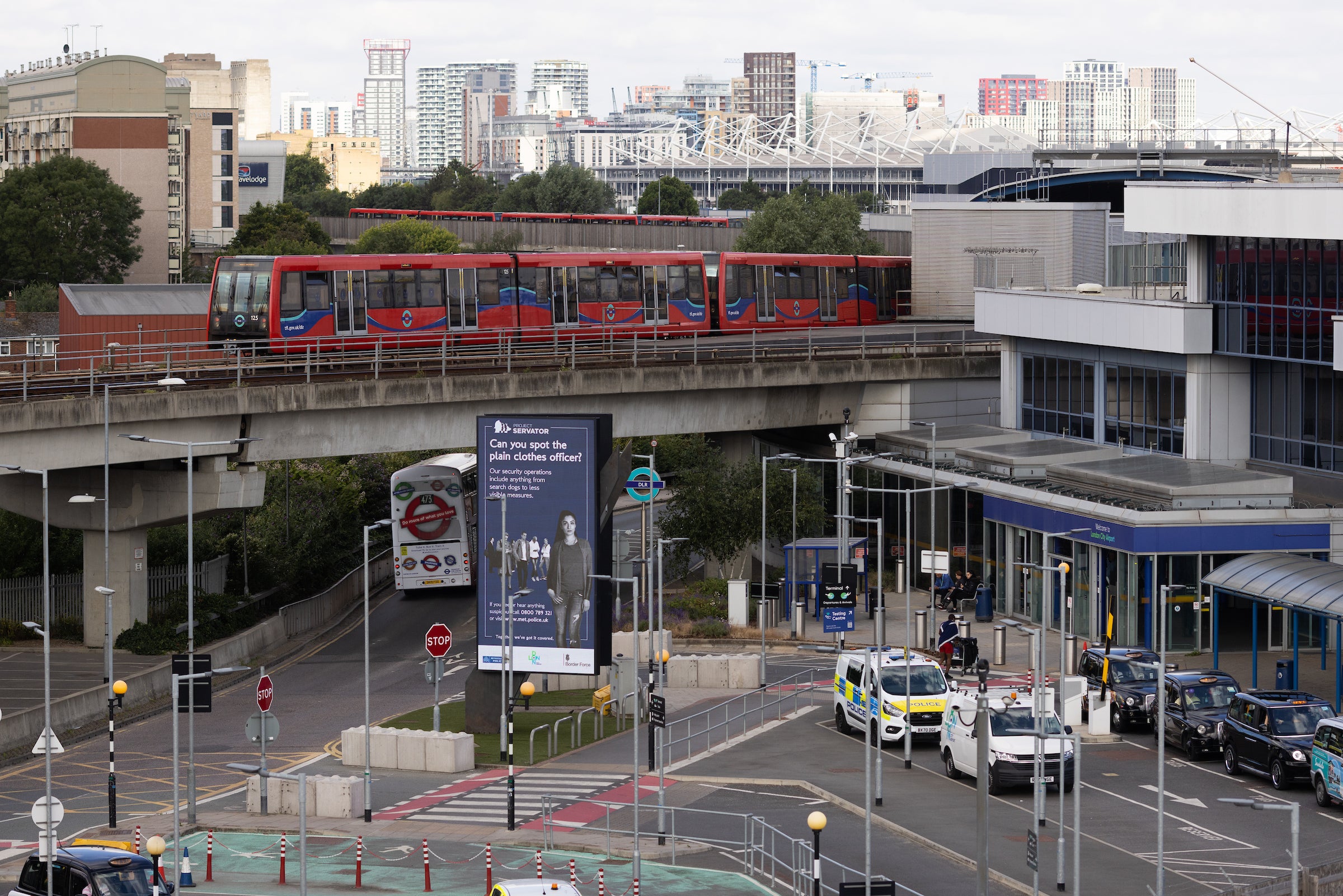<p>Charge zone: Forecourt of London City airport with Docklands Light Railway train on elevated line</p>