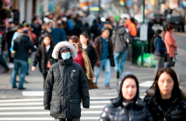 <p>People wear face masks as they walk down a street in New York City in March 2020. Health officials said two more children died of flu this week in the U.S.</p>
