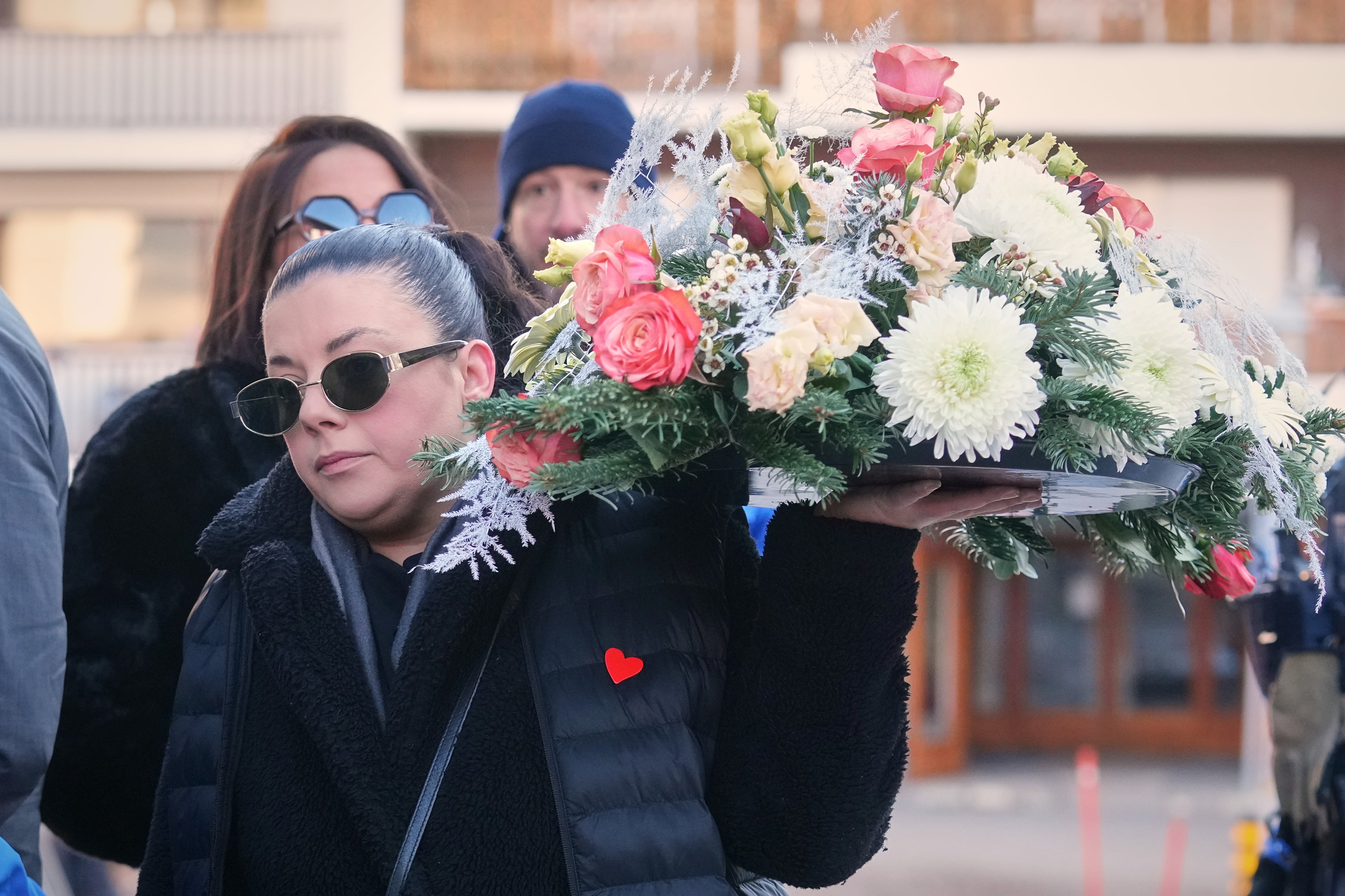 A woman holds a wreath outside the Chapelle St-Christophe during a memorial mass in Crans-Montana