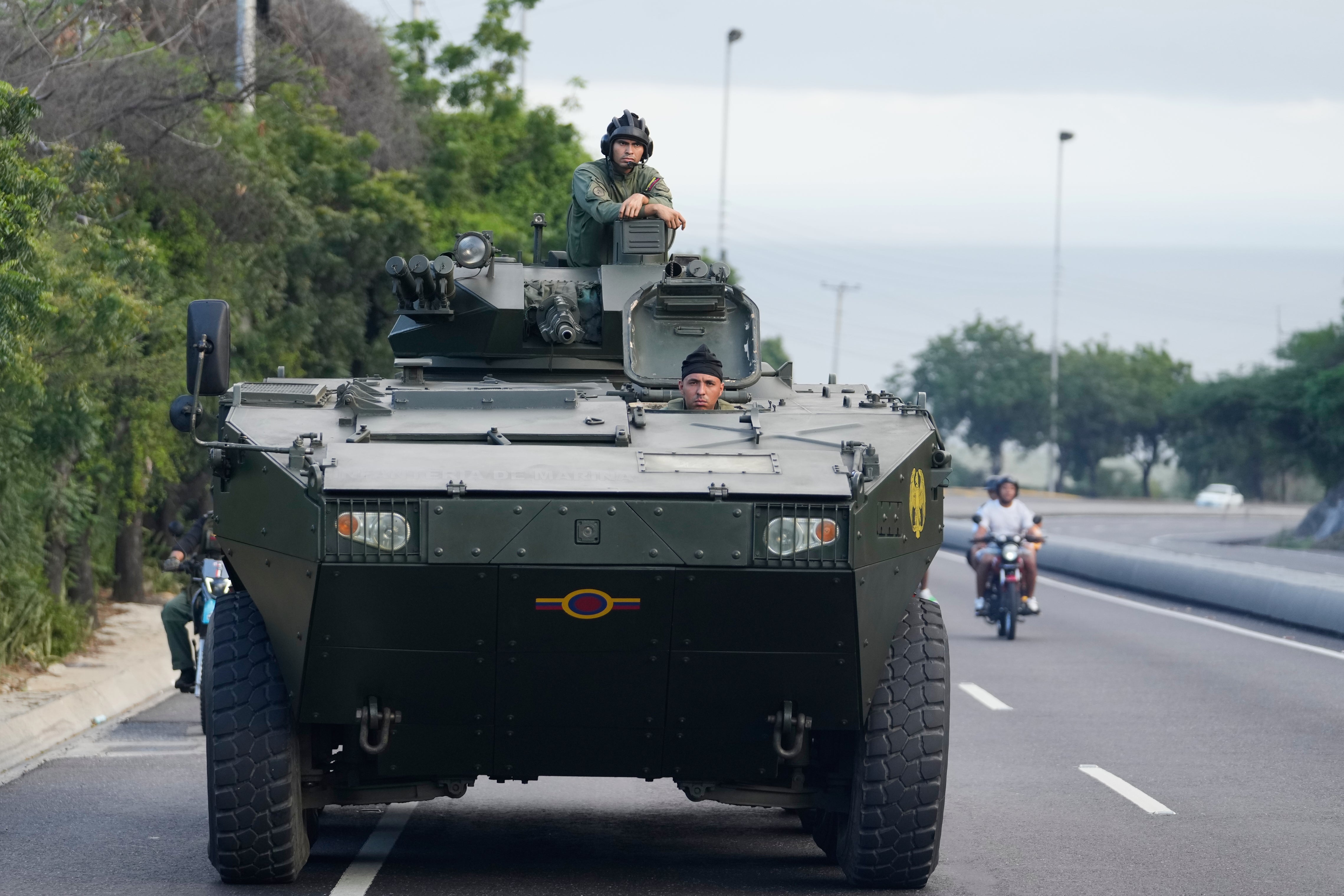 A soldier stands atop an armored vehicle on the highway leading from the international airport toward Caracas, Venezuela, Sunday, Jan. 4, 2026. (AP Photo/Matias Delacroix)