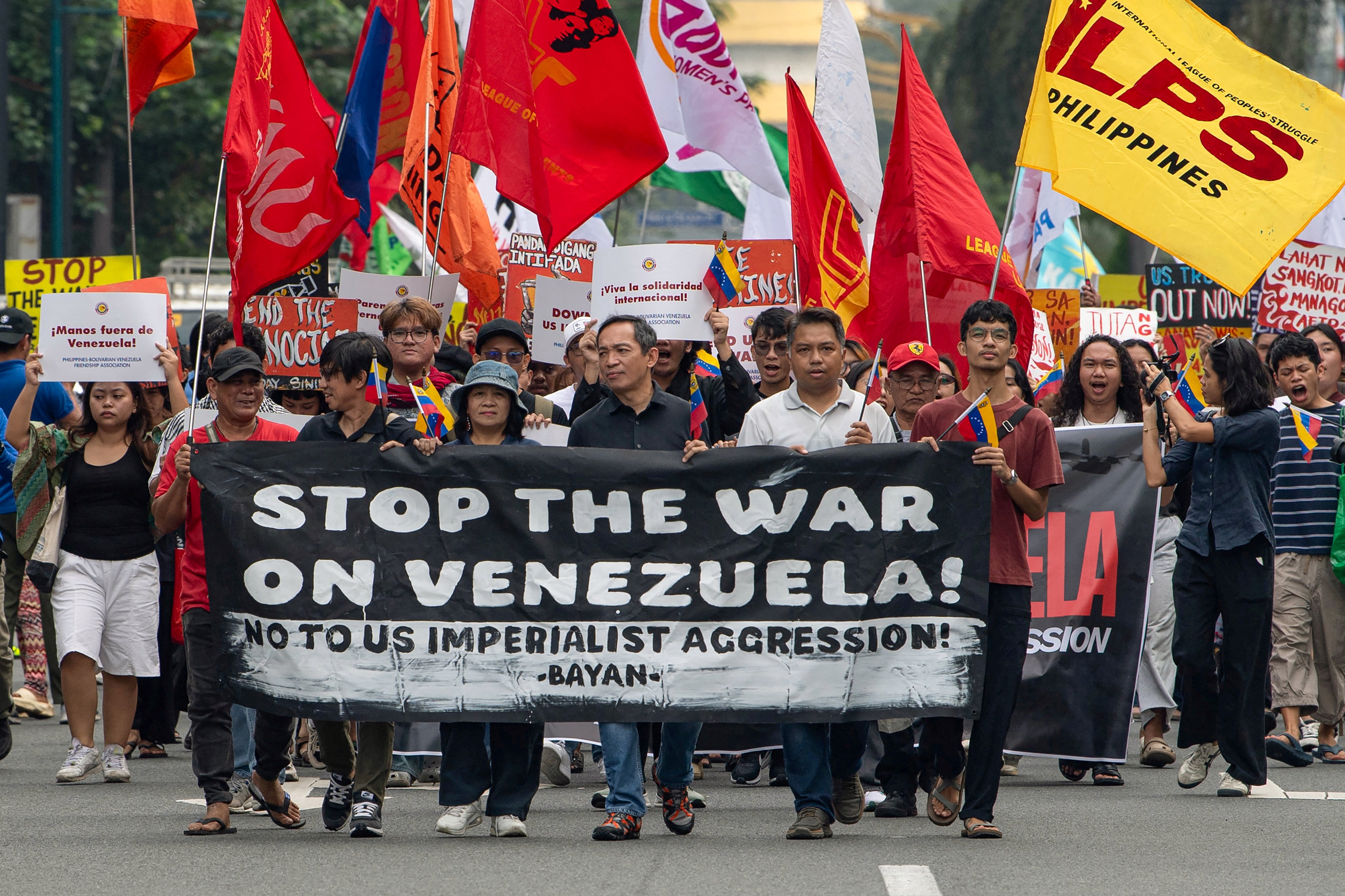 Protesters with flags and and a banner march during a demonstration condemning the US attack on Venezuela and the seizure of Venezuelan leader Nicolas Maduro, near the US embassy in Manila