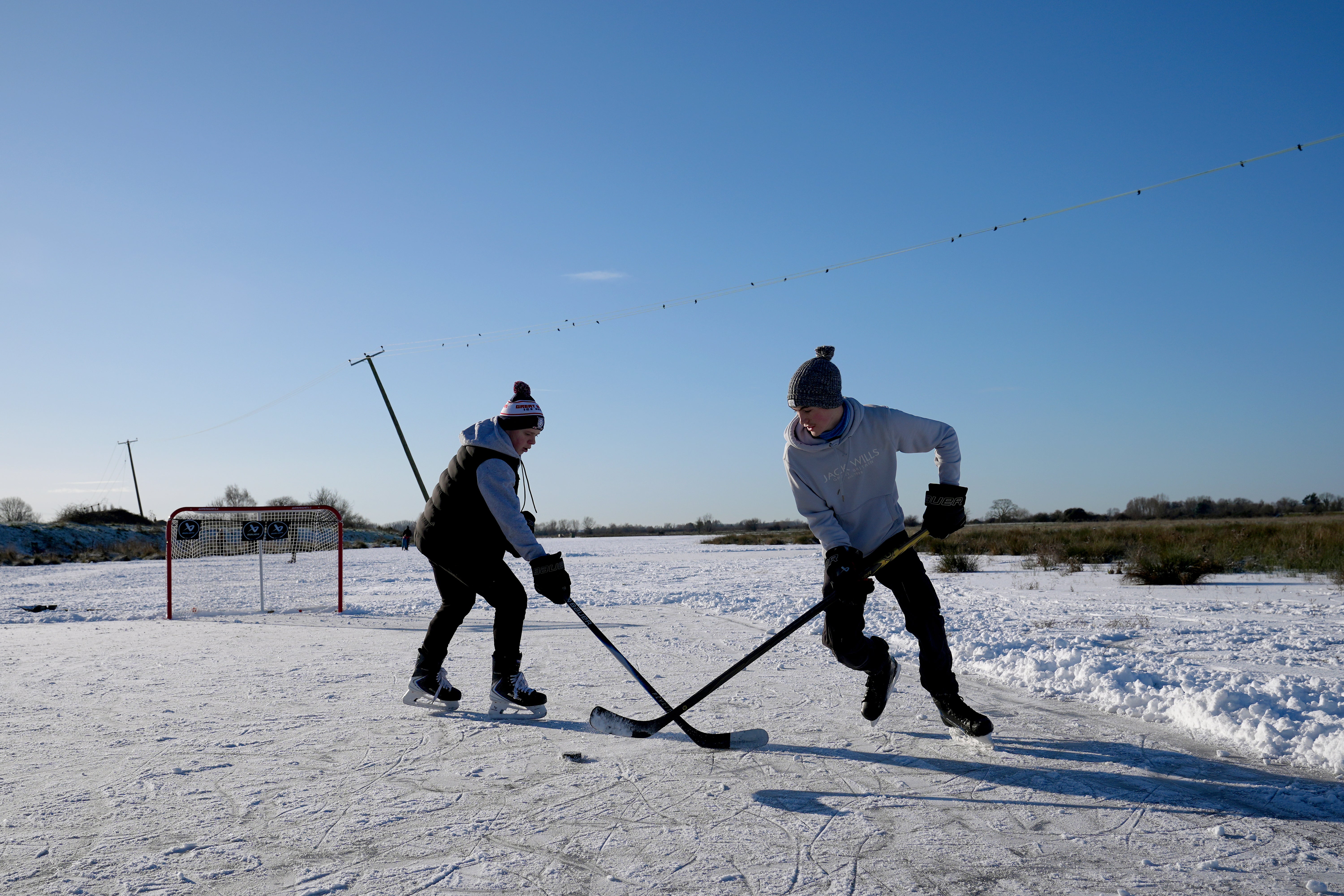People play ice hockey on a frozen flooded field in Upware, Cambridgeshire