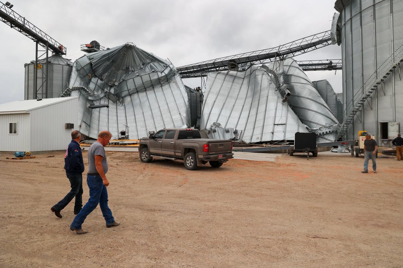 North Dakota Governor Kelly Armstrong walks by silos damaged by an EF5 tornado in Enderlin last June