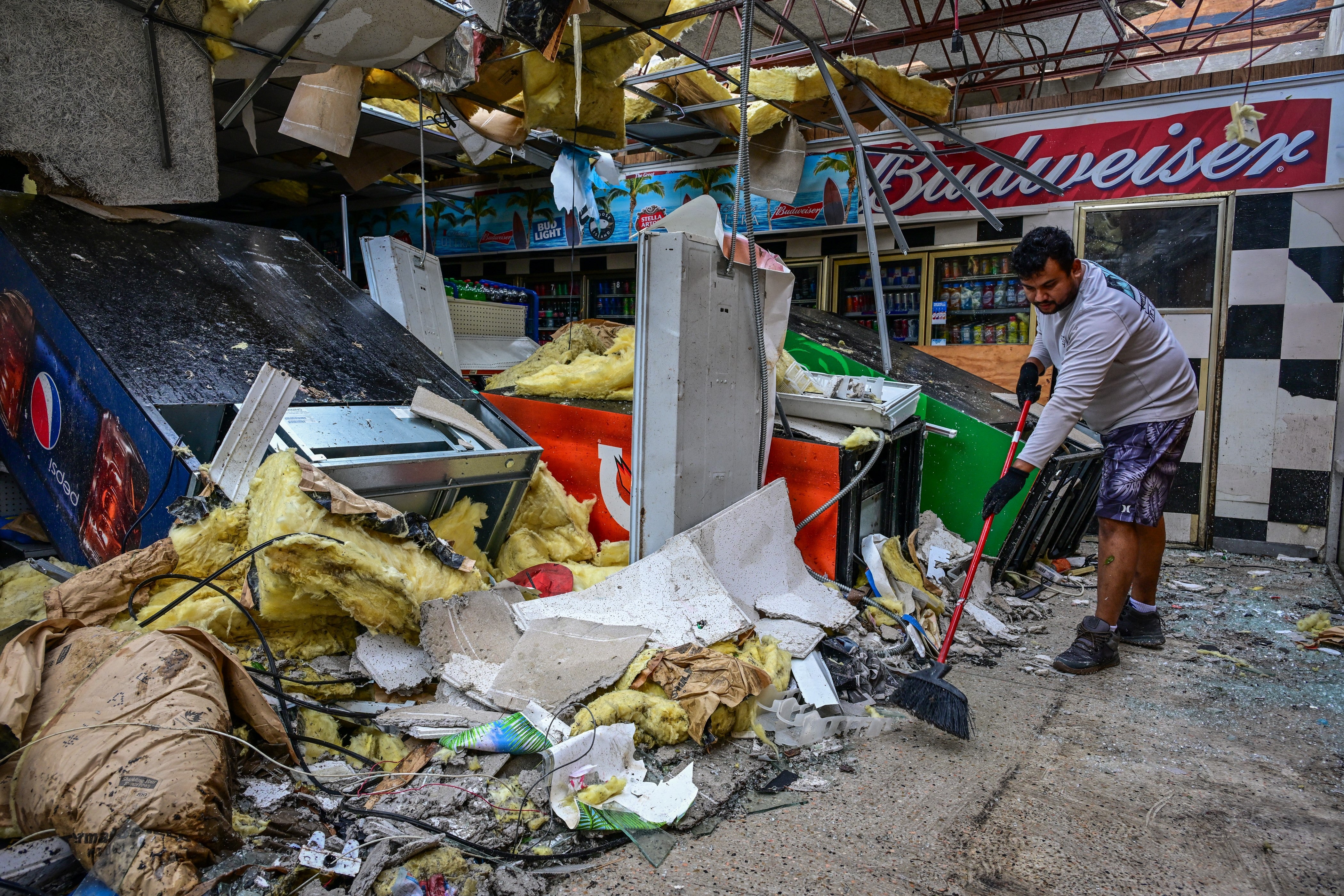 A man cleans debris inside a Florida gas station Florida following a tornado caused by Hurricane Milton in October 2024