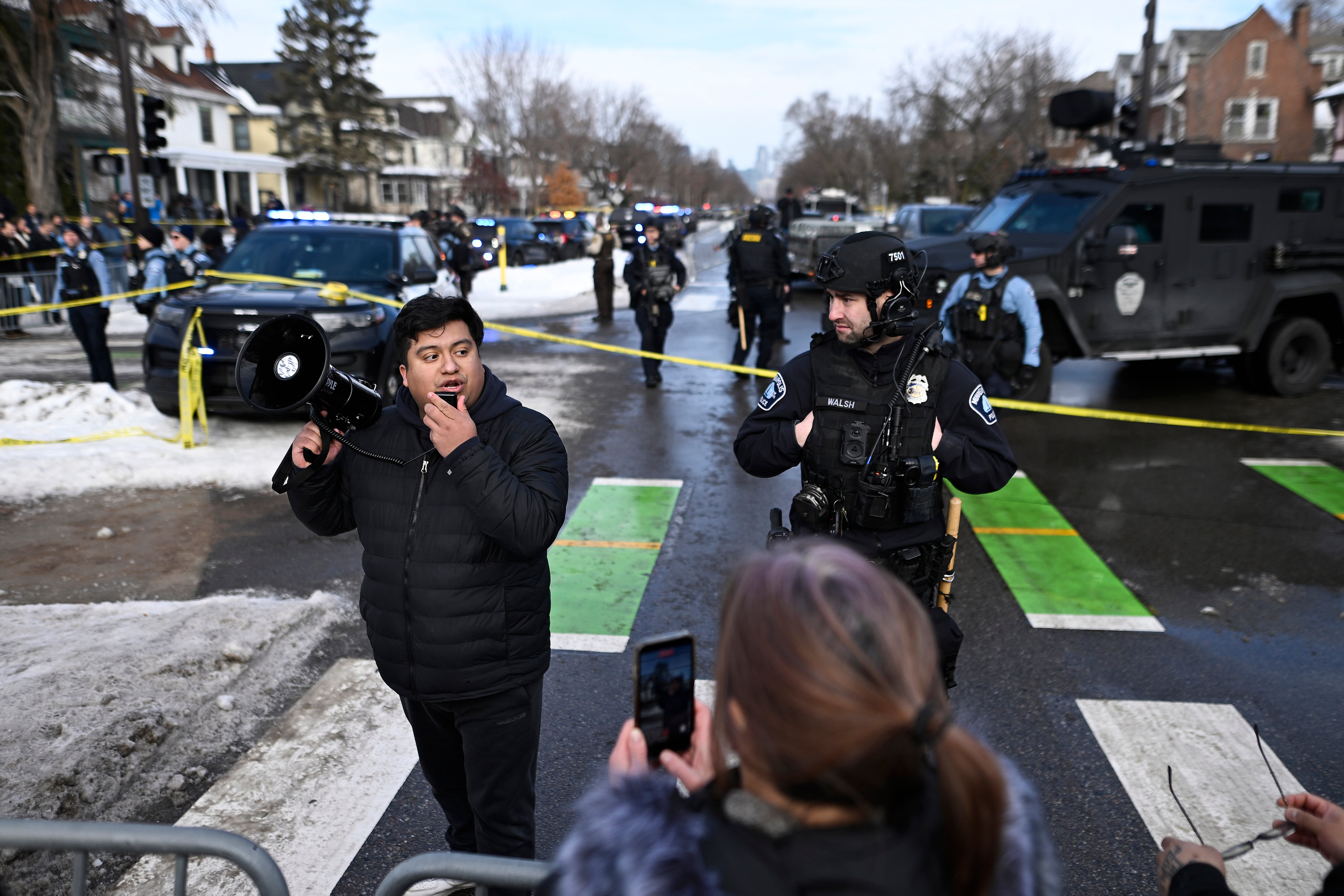 Minneapolis City Council member Jason Chavez addressed onlookers while flanked by a law enforcement officer
