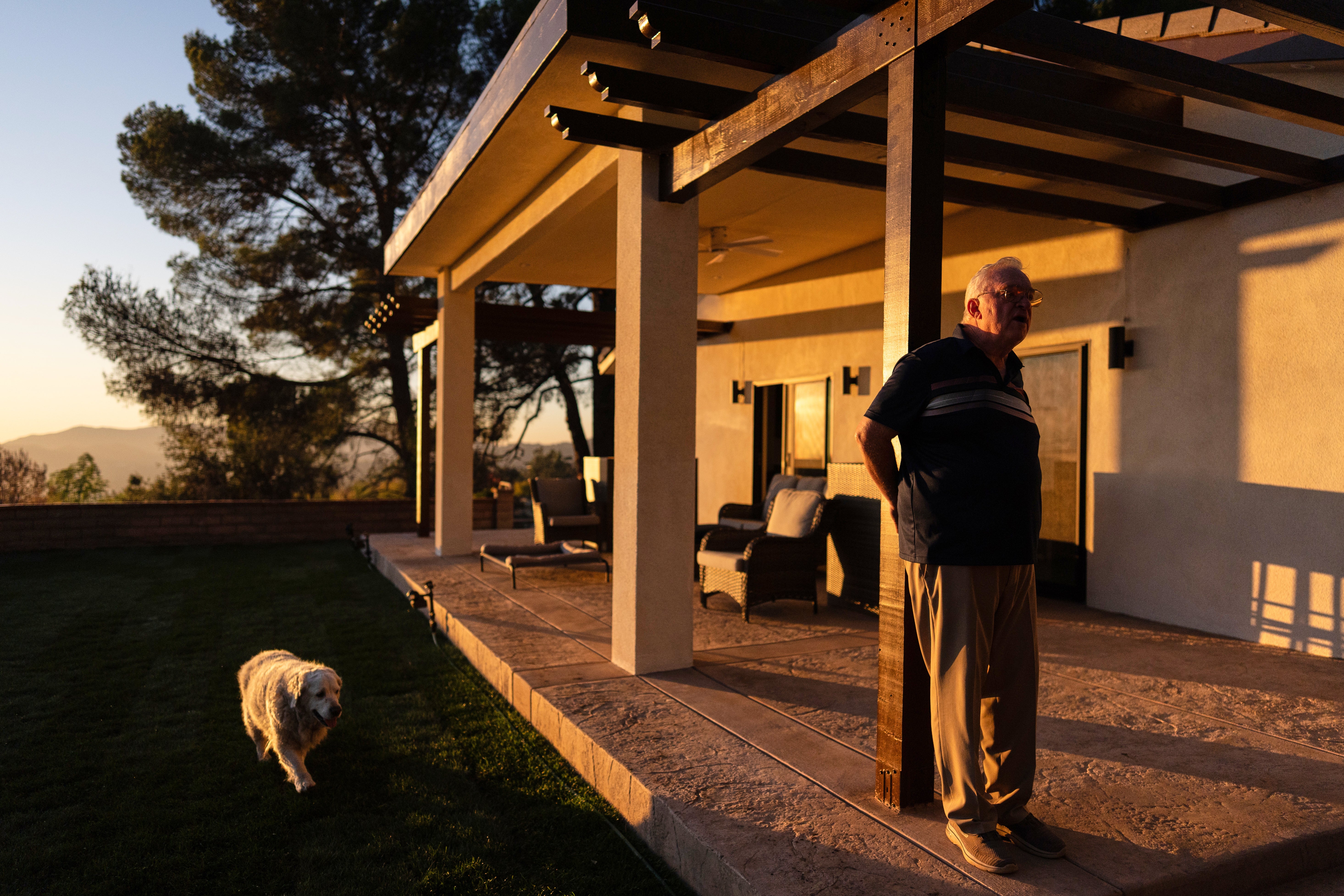 Ted Koerner, whose home was reduced to ash in the 2025 wildfires, stands on the porch of his newly rebuilt home, alongside his dog Daisy Mae, in Altadena, Calif., Dec. 11, 2025