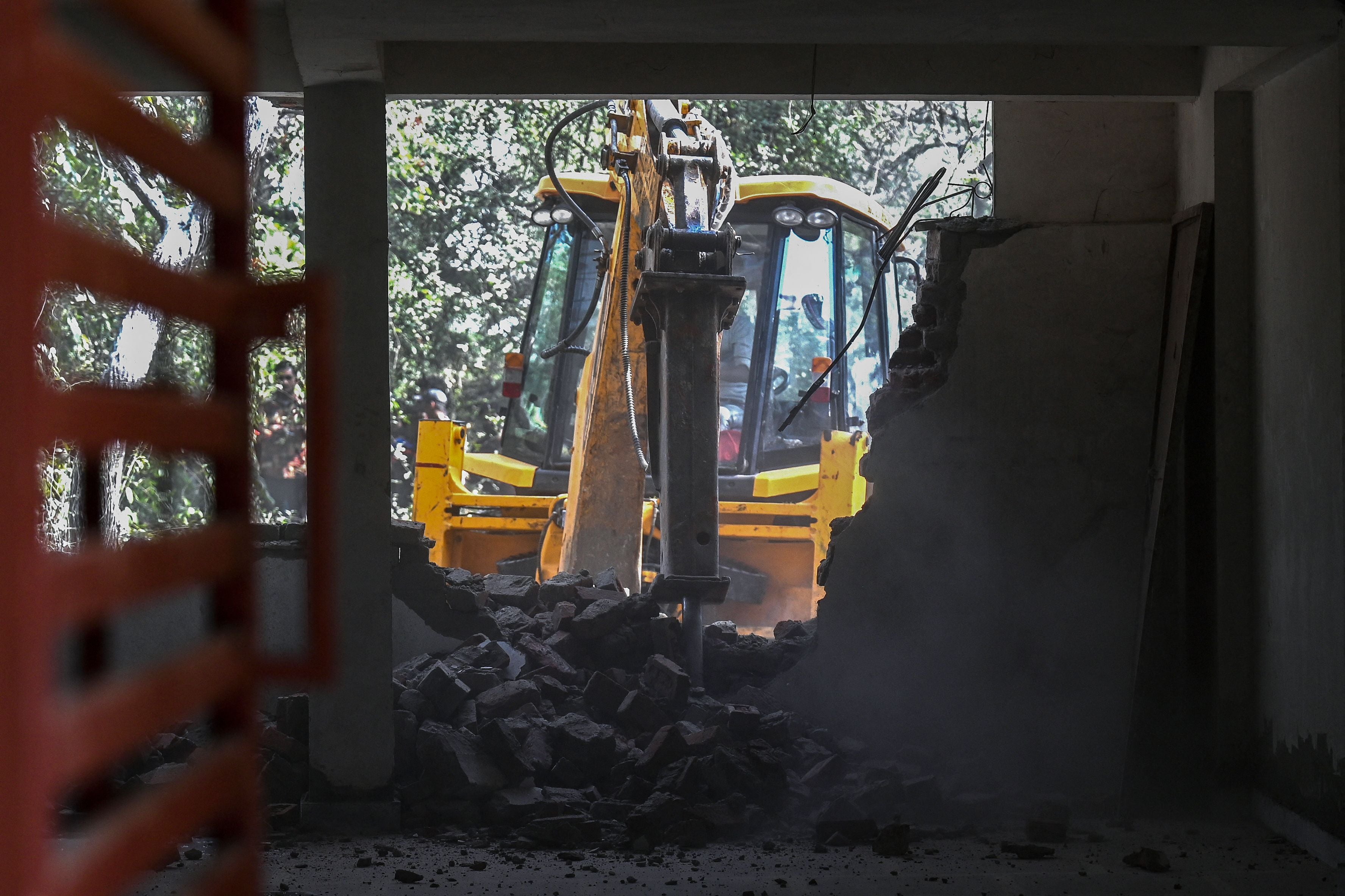File. A backhoe demolishes a building in Mehrauli, Delhi