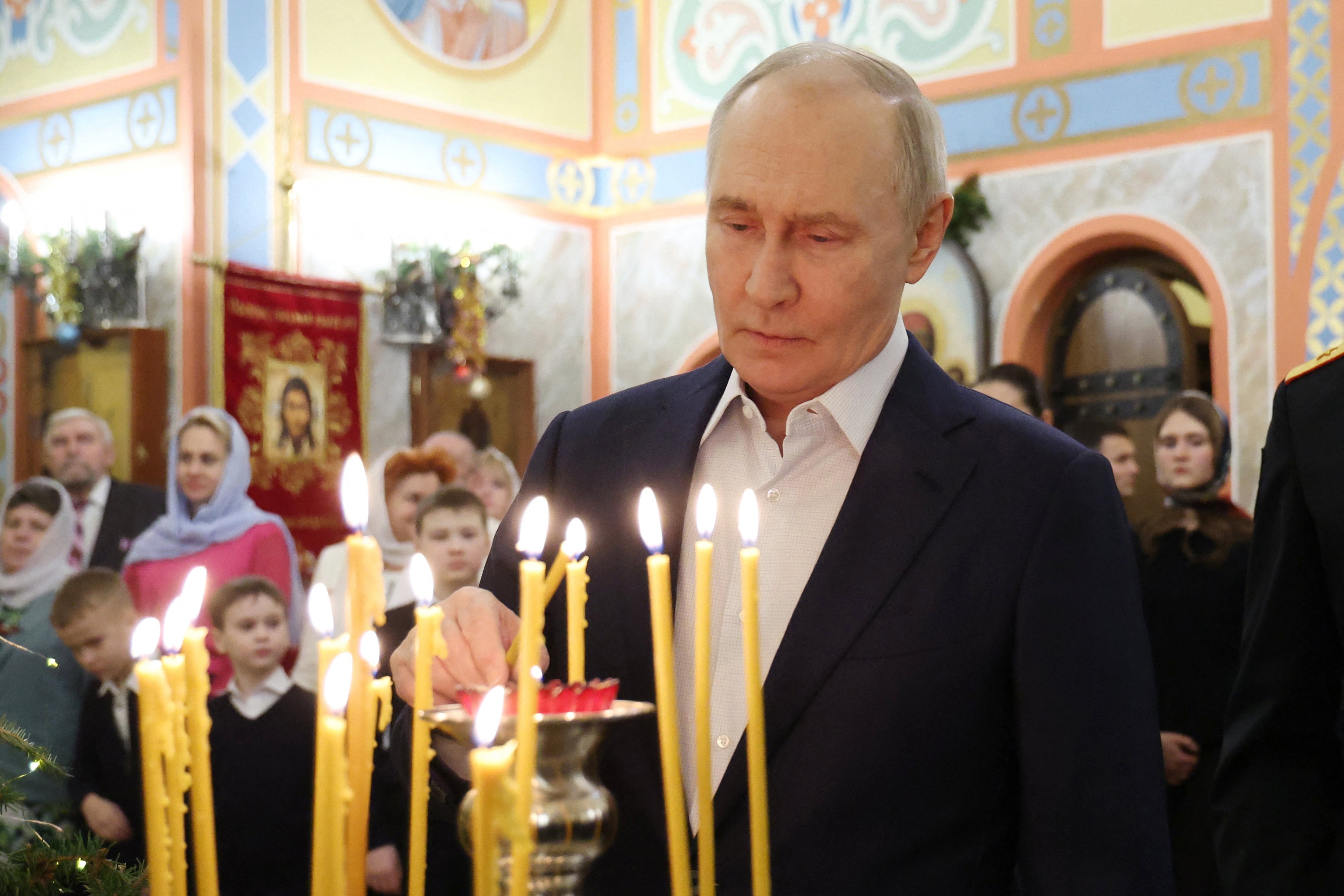 Vladimir Putin lights a candle as he attends a Christmas service at a church in Moscow