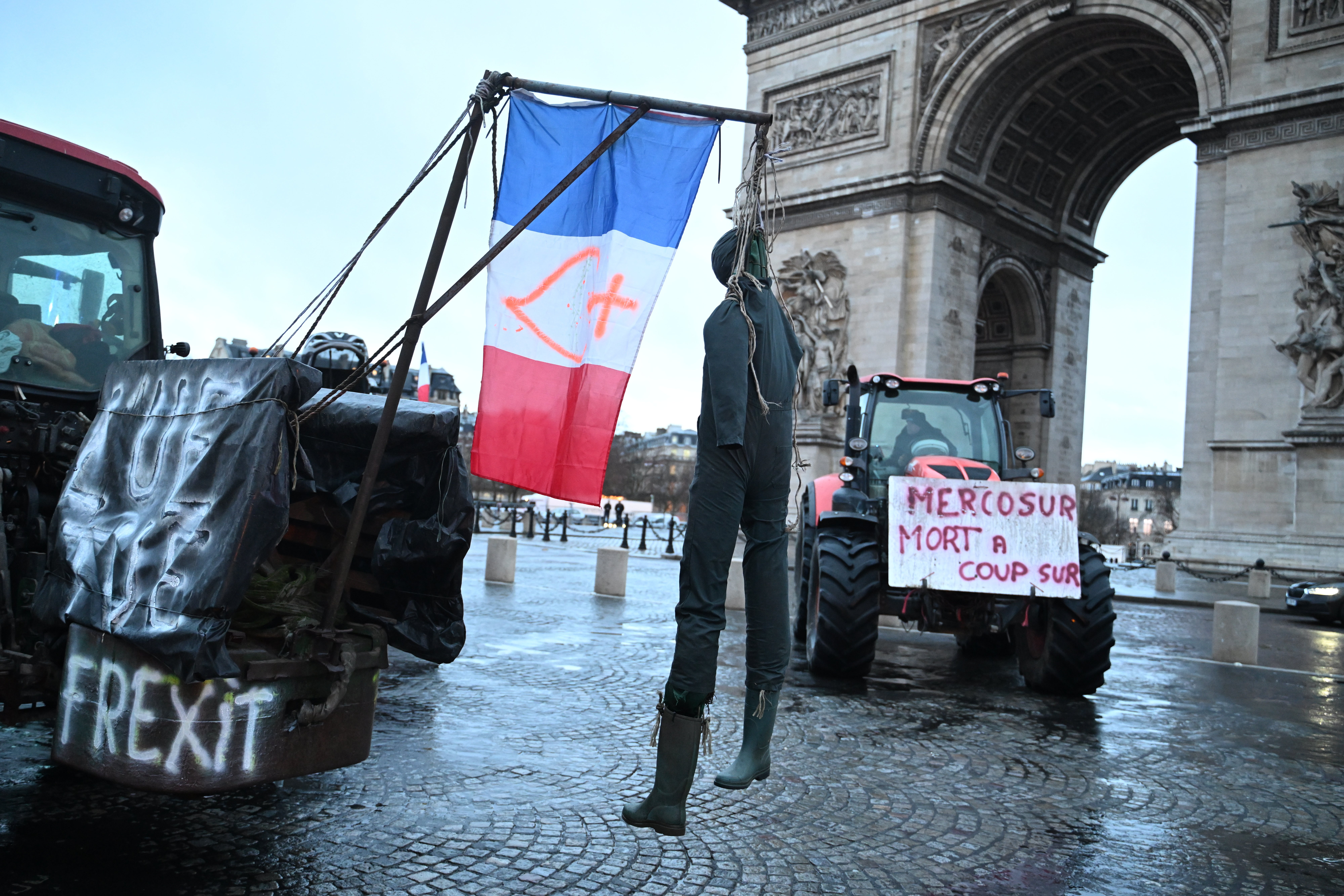 A mannequin hangs from a tractor as farmers protest at the Arc de Triomphe against the Mercosur trade alliance with South America countries but also against EU farming policy or mass cull of cows ordered to contain the spread of a skin disease, Thursday, Jan. 8, 2026 in Paris. Poster at right reads: Mercosur, death for sure.